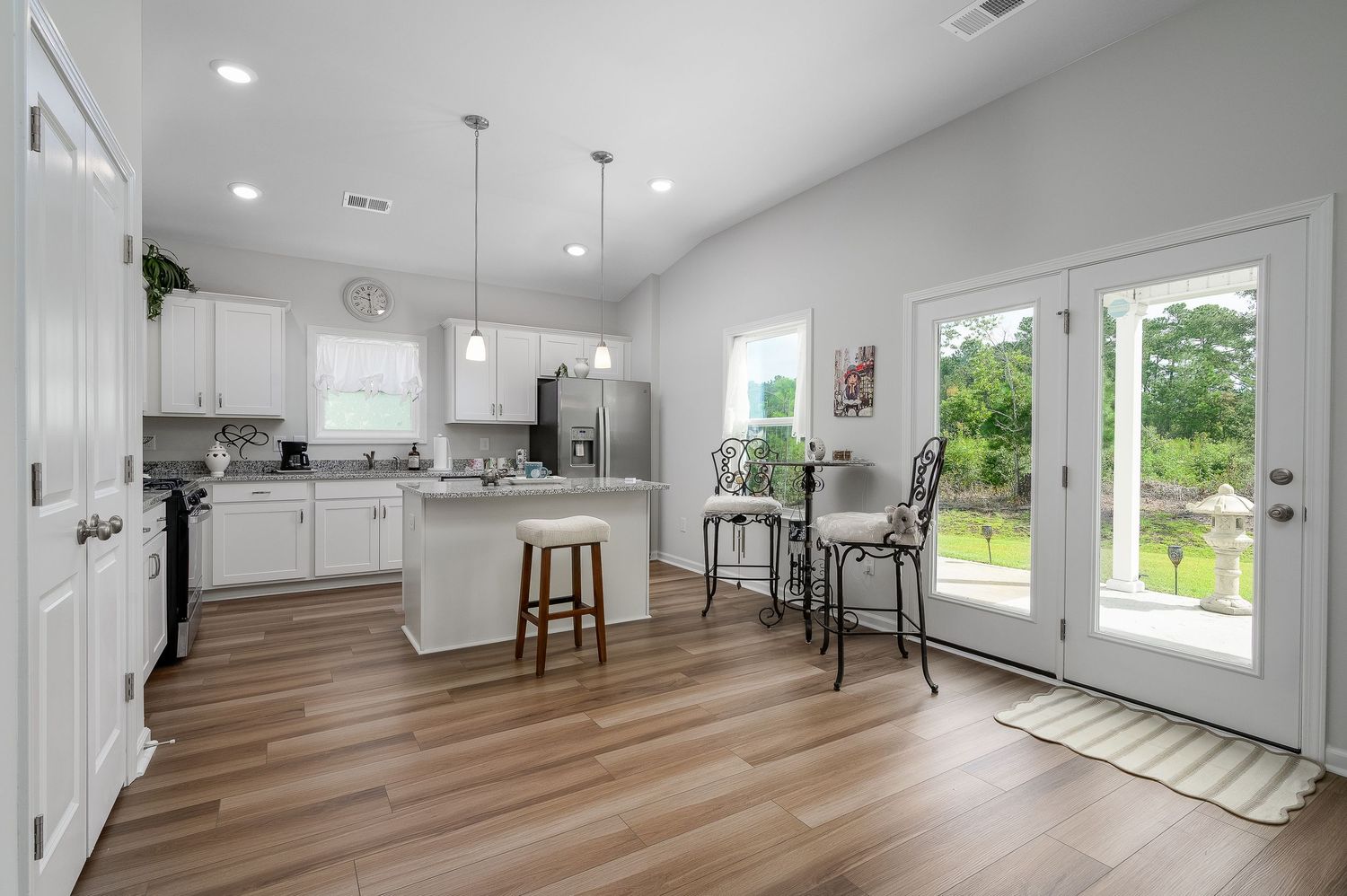 Spacious kitchen with white cabinets, island, hardwood floors, and French doors to patio.