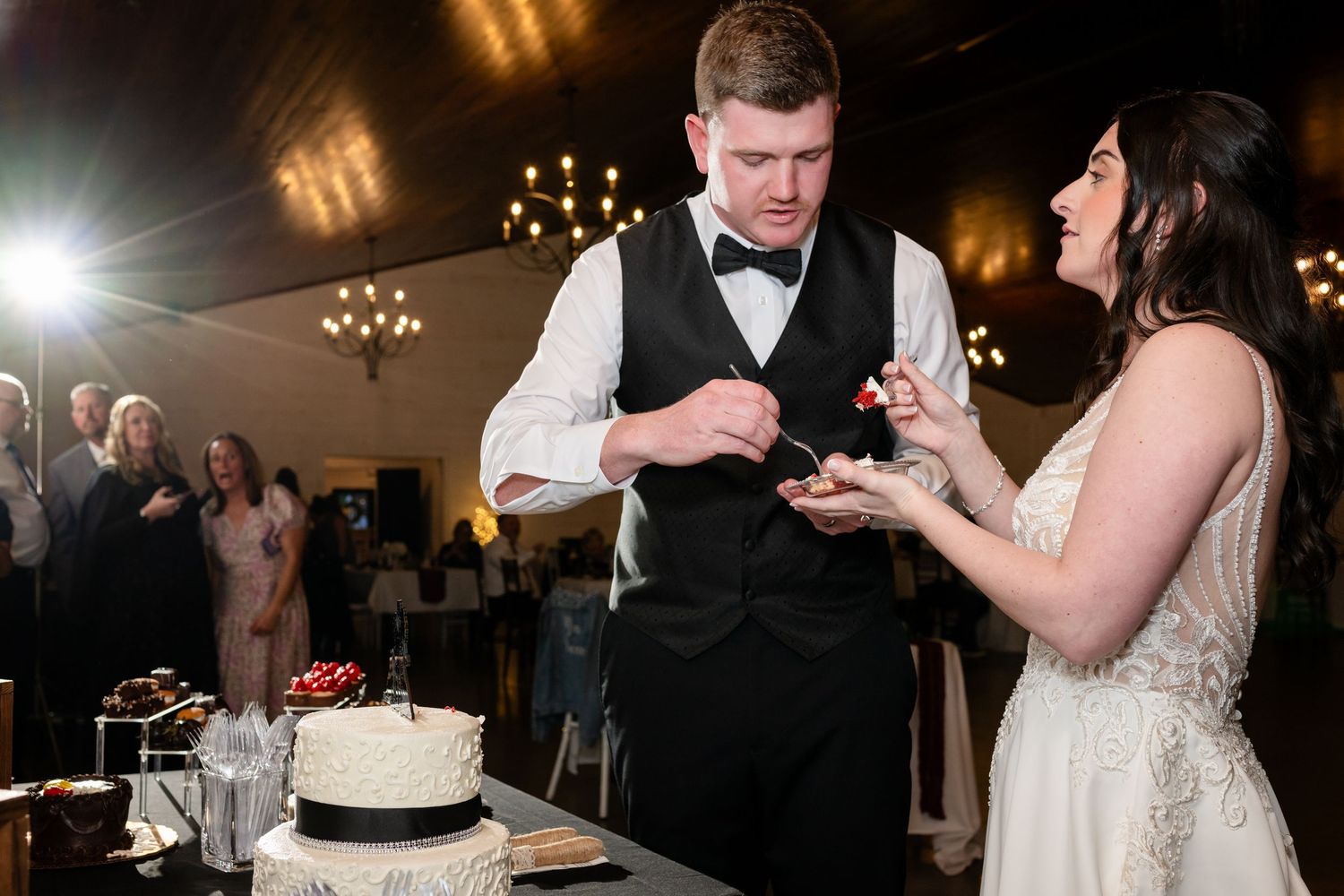 Bride and groom cutting their white wedding cake at elegant indoor reception.