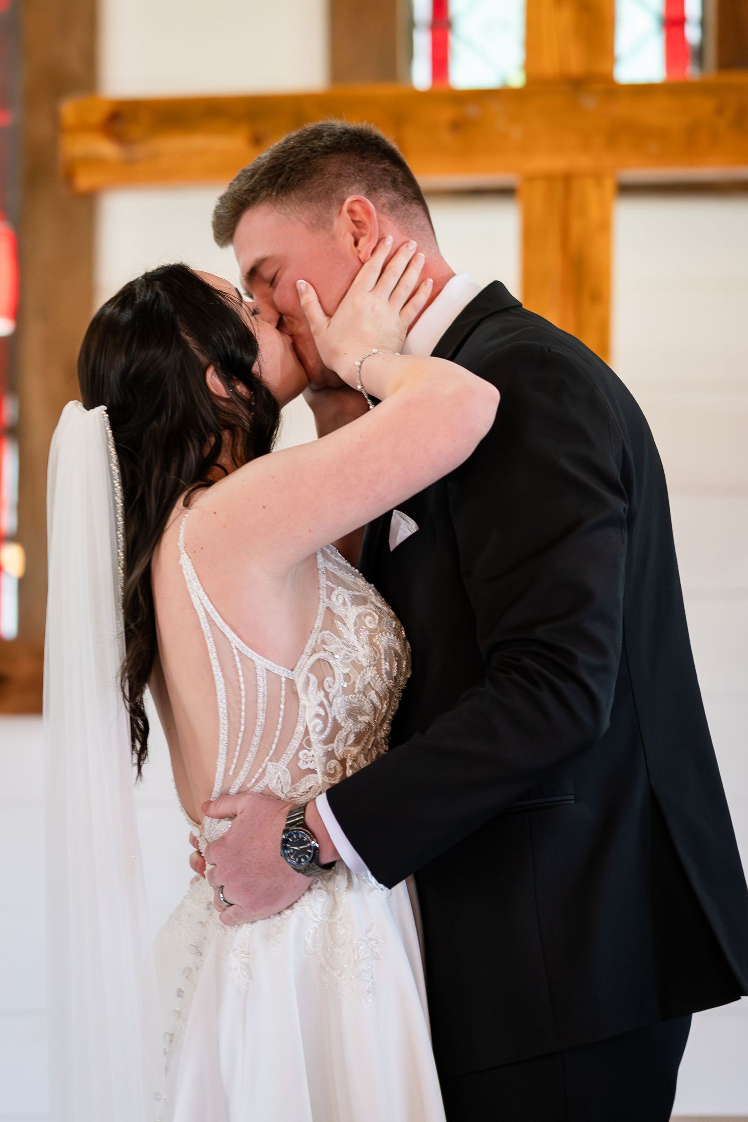 Bride and groom share first kiss at the altar in a white chapel wedding ceremony.