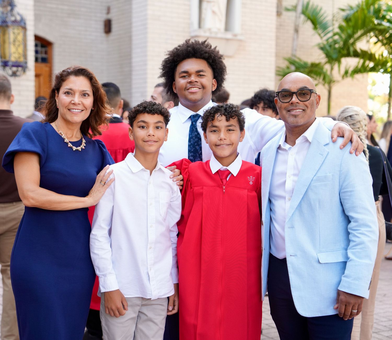 A family of five smiles together outdoors at a ceremony celebration.