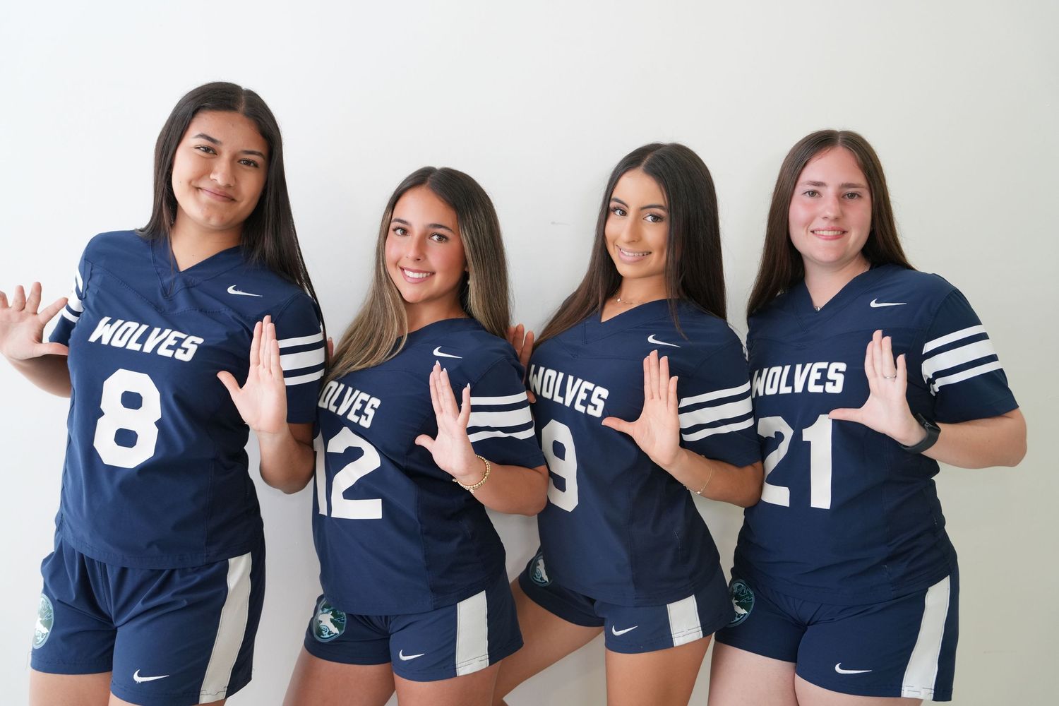 Four female athletes in navy Wolves jerseys numbered 8, 12, 9, and 21 pose together.