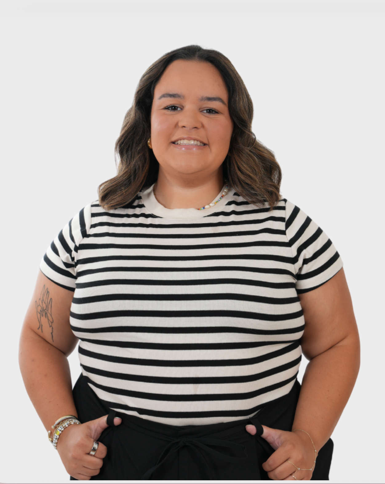 Smiling woman in striped black and white tee poses confidently against white background.