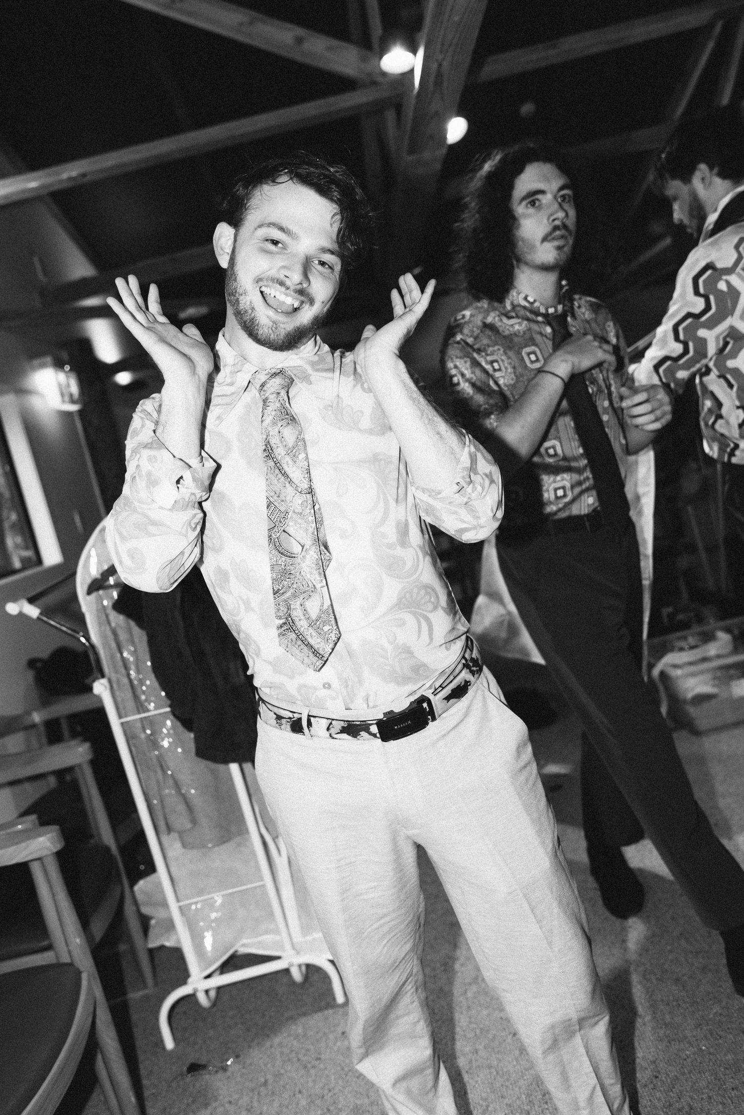 Black and white photo of a guest dancing energetically at a wedding reception.