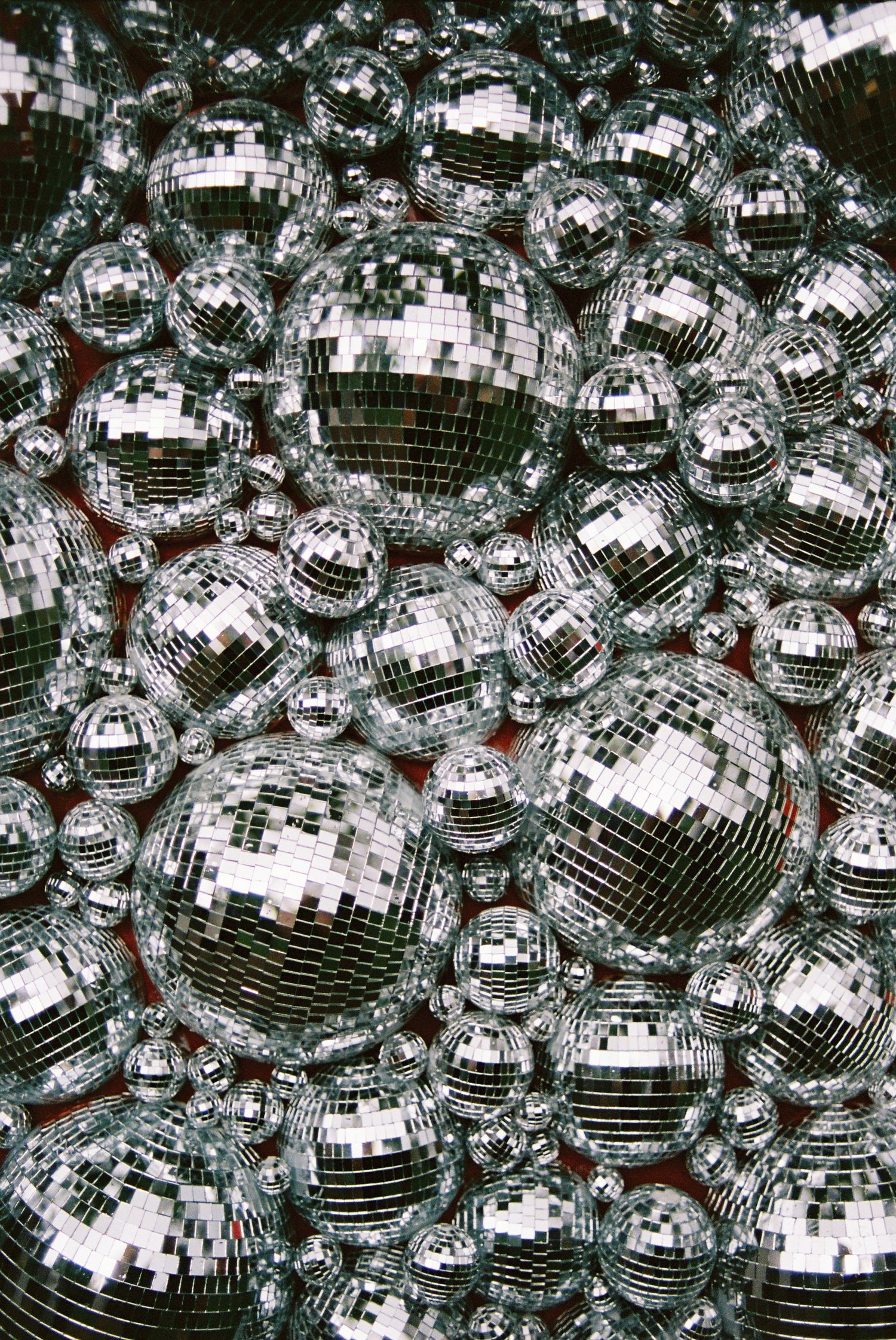 Large collection of silver mirror disco balls of various sizes clustered together.