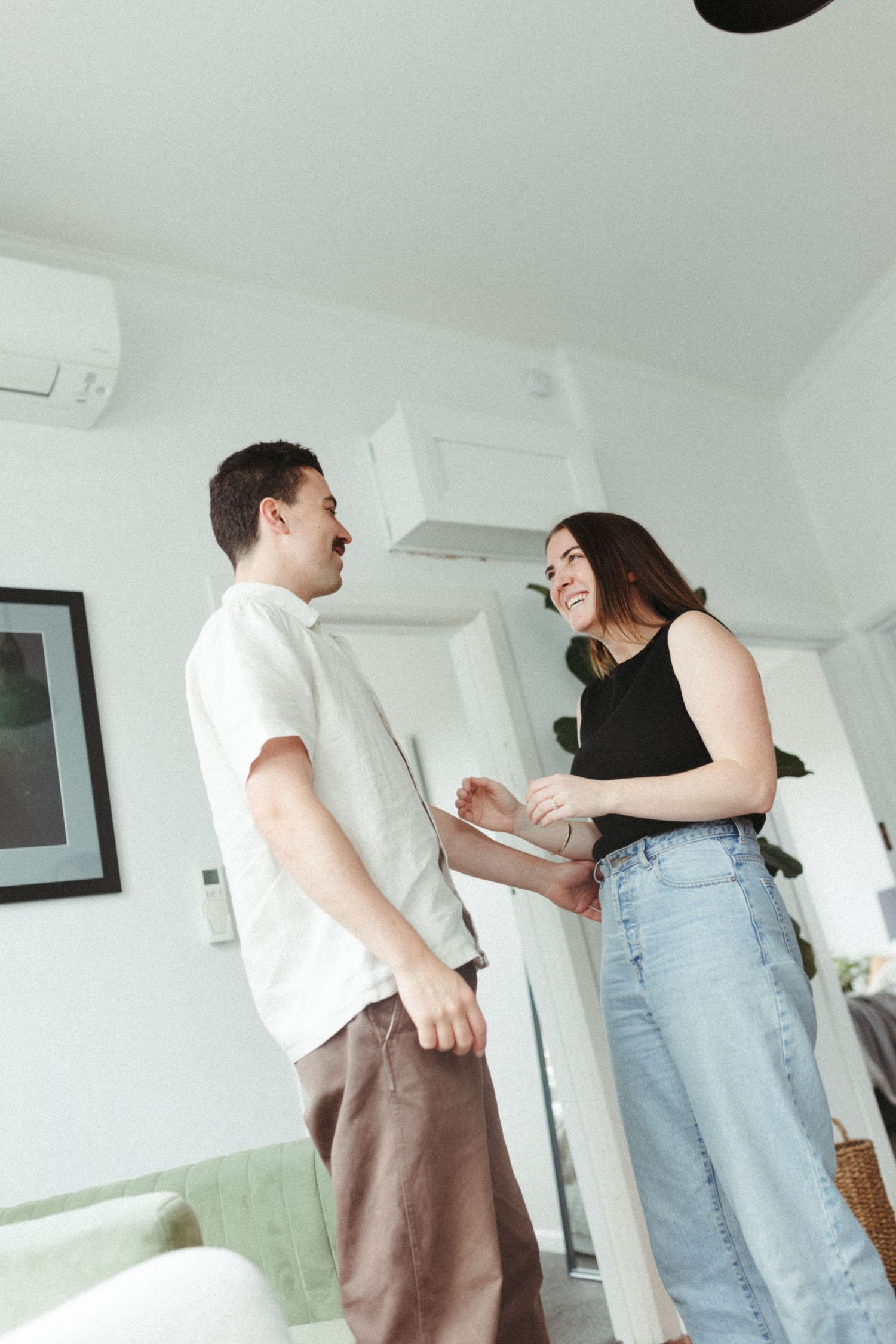Smiling couple standing together in a bright modern apartment with air conditioning unit.