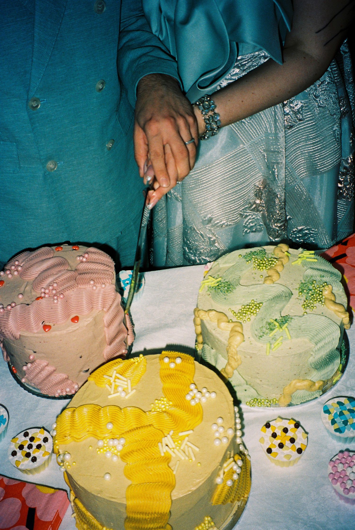 Bride and groom cut colorful pastel wedding cakes decorated with vintage-style frosting details.