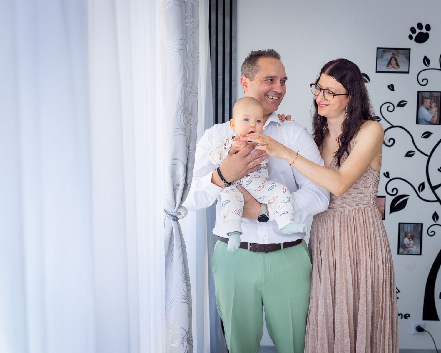 Eltern halten Milan bei einem Familienmoment am hellen Fenster