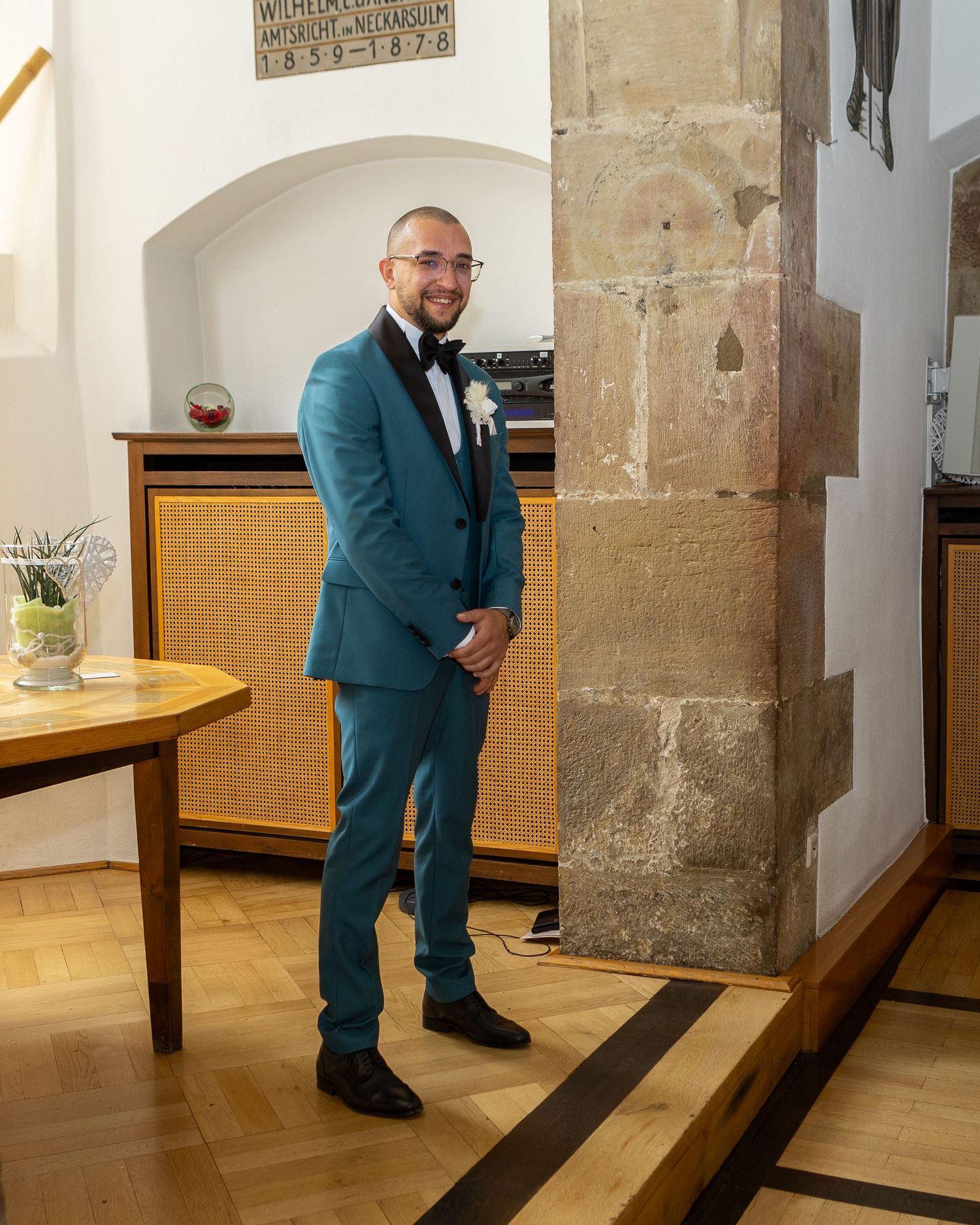 Bräutigam wartet neben einer steinernen Säule im Innenraum der Kirche.