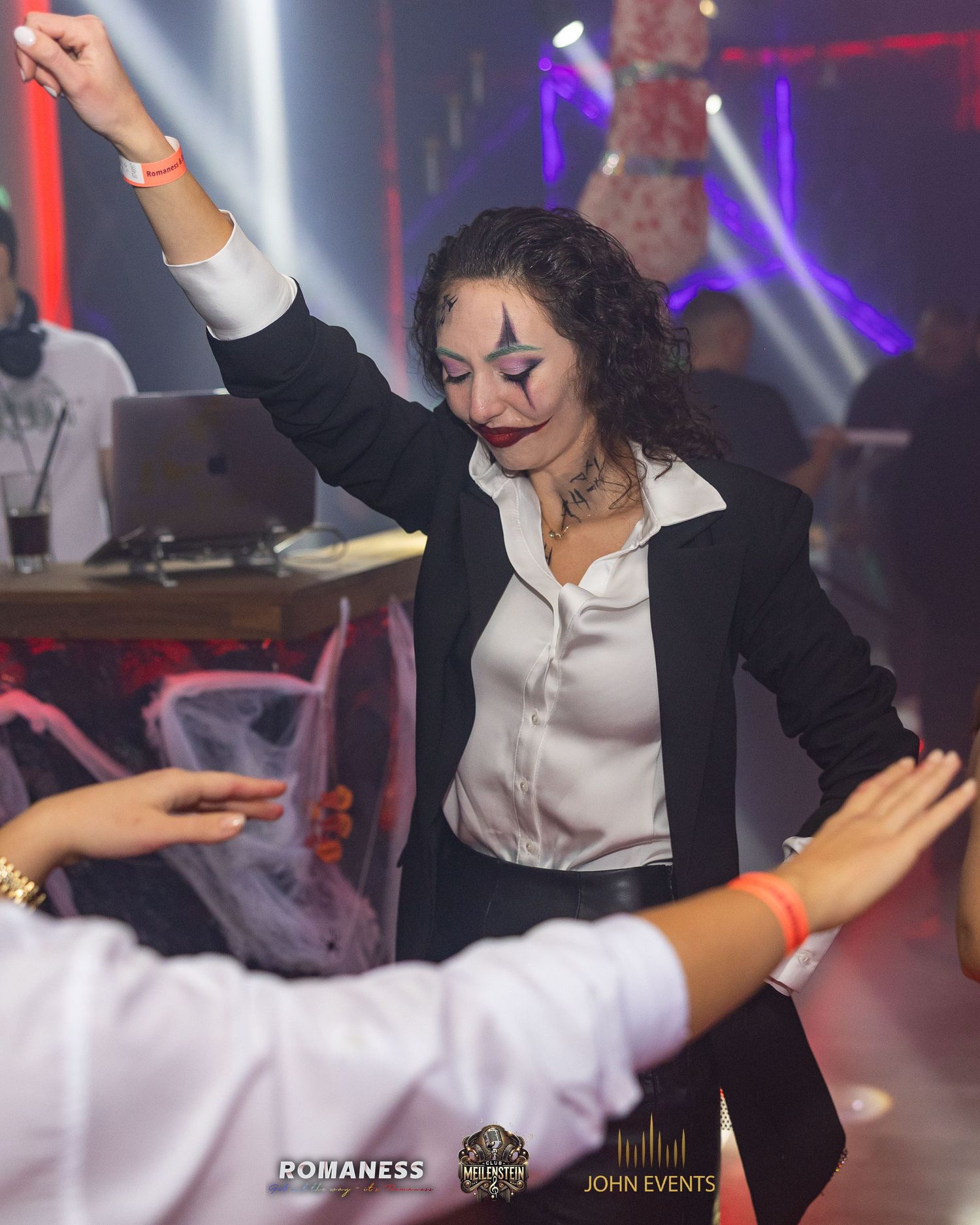 Eine verkleidete Frau tanzt mit erhobenem Arm zwischen Gästen im Club Meilenstein.