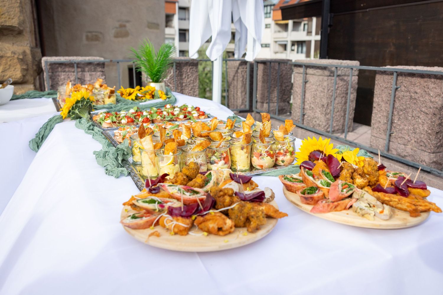 Das Buffet auf der Terrasse mit belegten Platten unter einem weißen Sonnenschirm.