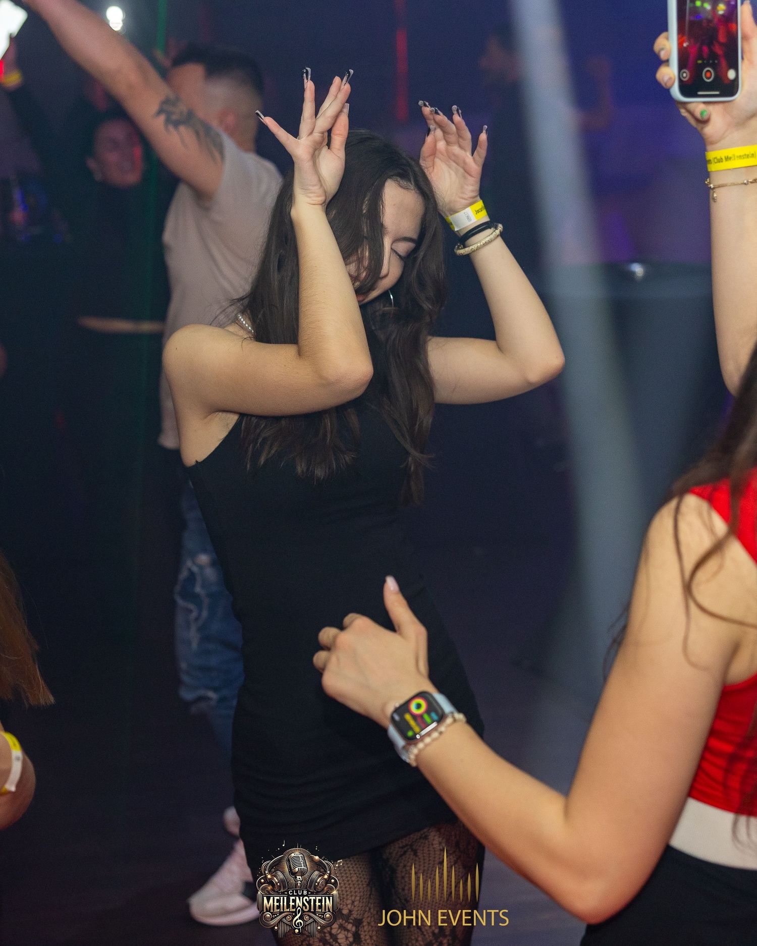 Eine Frau hebt beim Tanzen im Club Meilenstein beide Hände neben ihren Kopf.