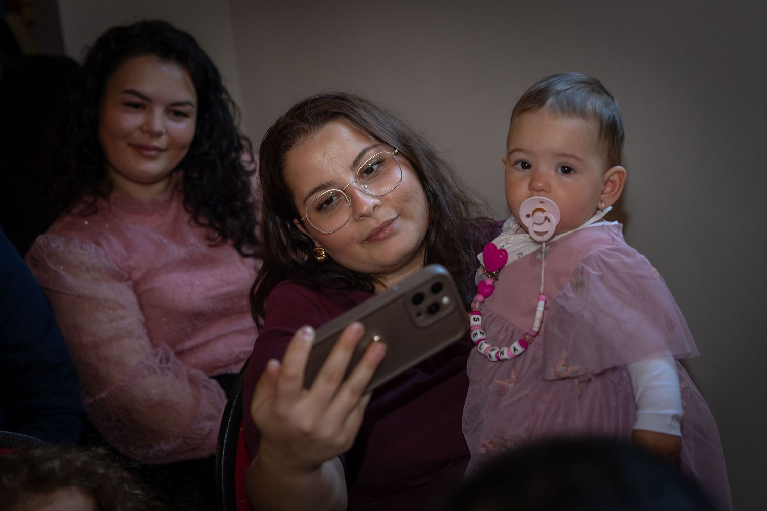 Eine Frau hält ein Kind zwischen den wartenden Gästen in der Kirche