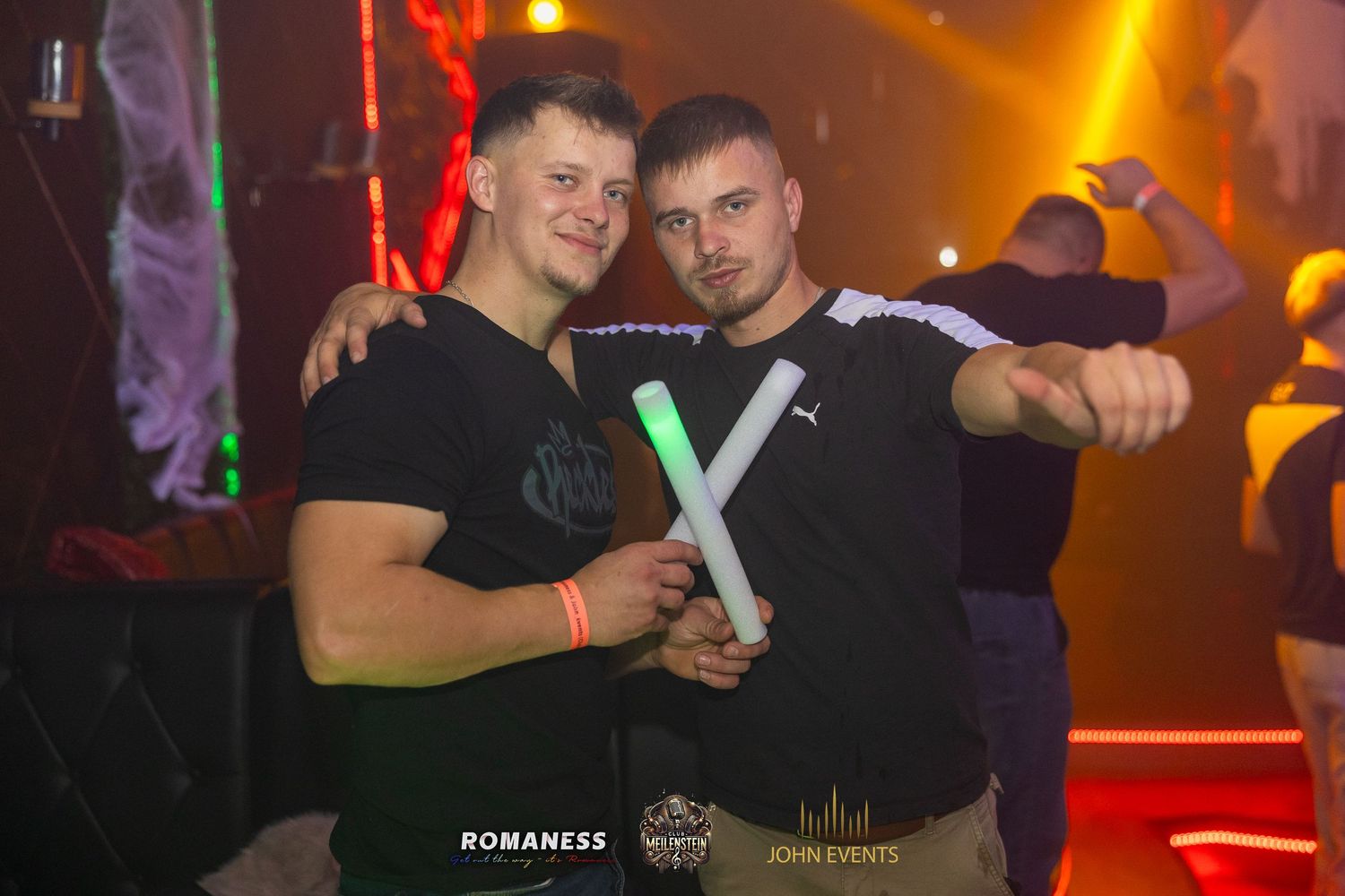 Zwei Männer halten leuchtende Stäbe bei der Halloweenparty im Club Meilenstein.