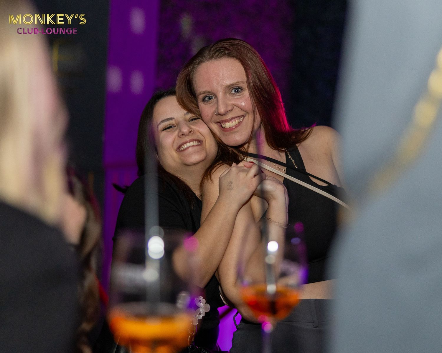Zwei Frauen umarmen sich an einem Tisch im Monkey’s Club.