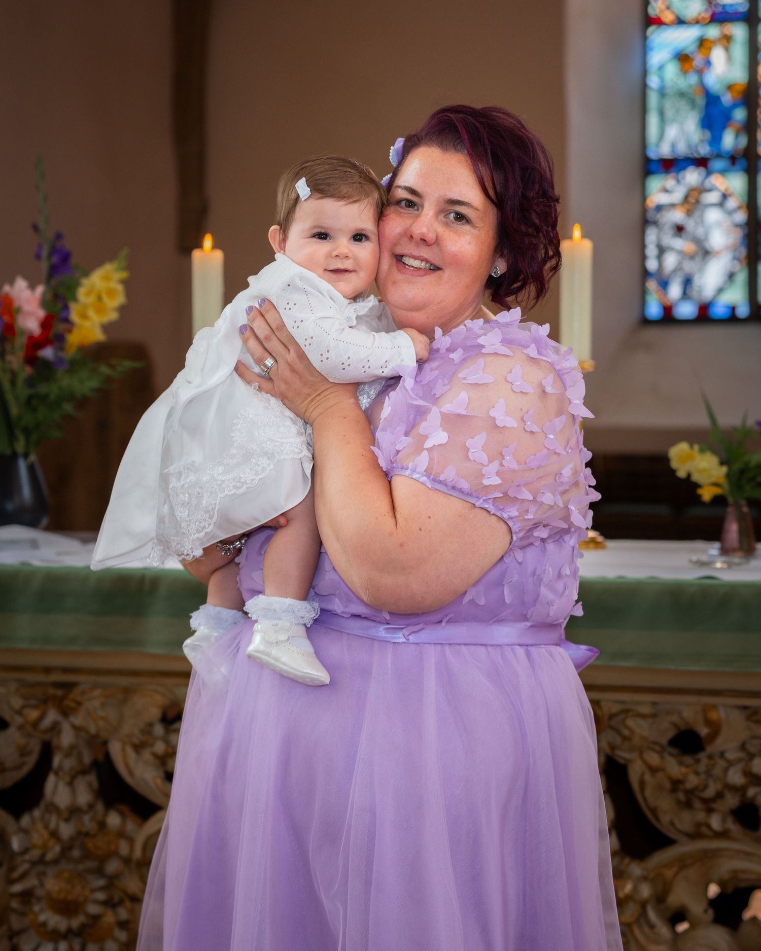 Karoline im weißen Taufkleid auf dem Arm ihrer Mutter in der Kirche.