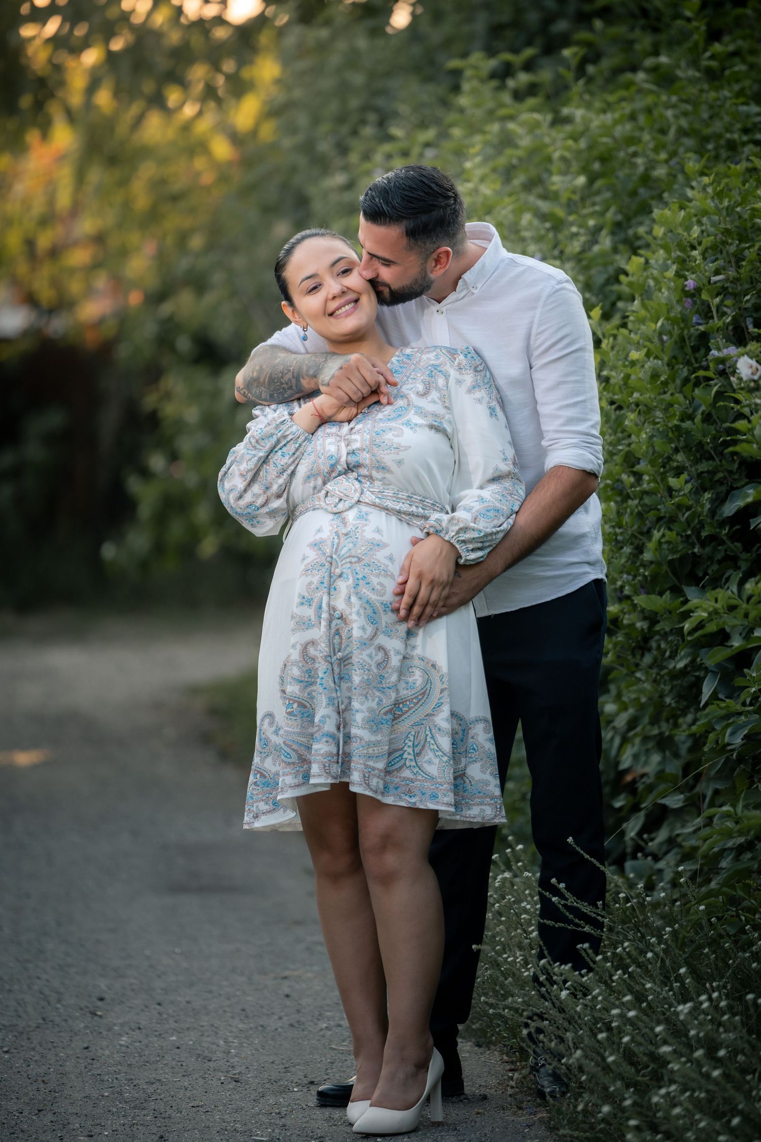 Cristina lächelt, während Claudiu sie an der Schläfe küsst und eine Hand an ihren Bauch legt.