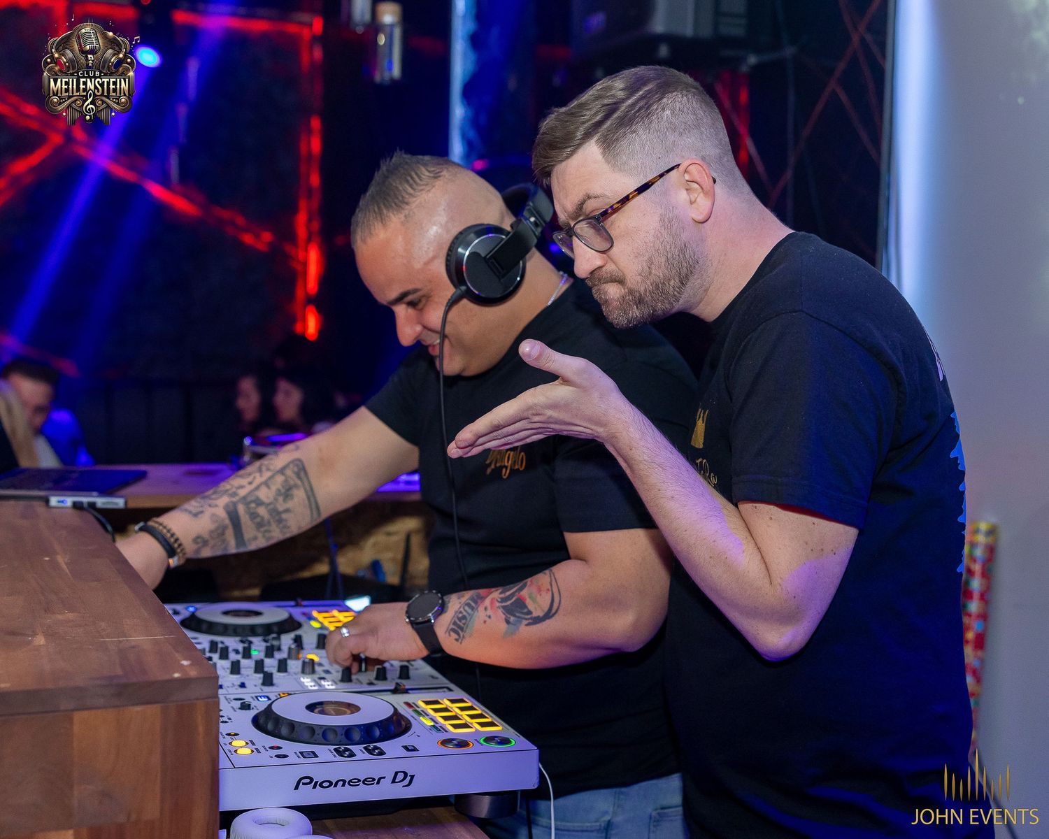 Zwei Männer arbeiten gemeinsam am DJ-Pult im Club Meilenstein.