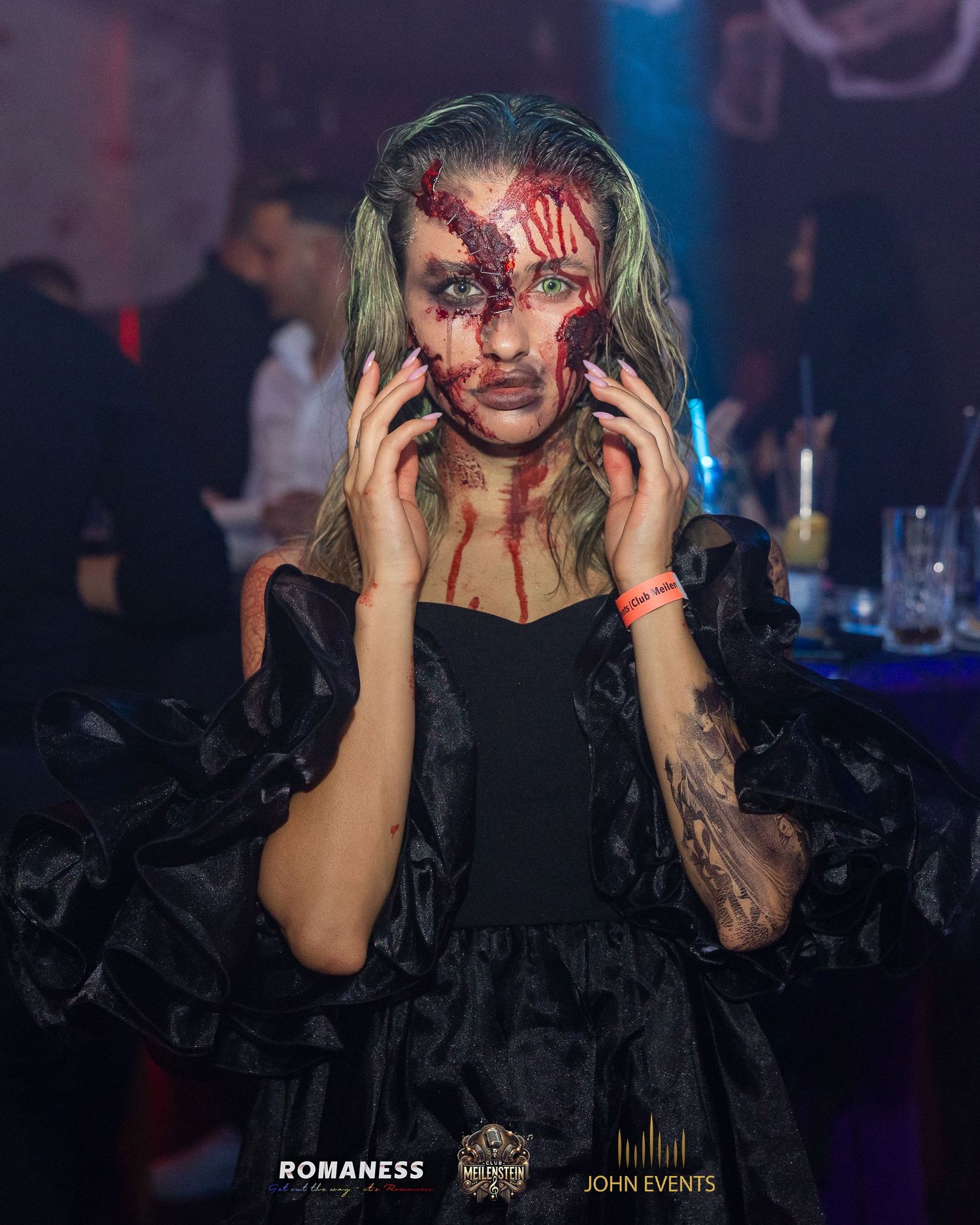 Eine Frau mit aufwendigem Halloween-Make-up hält die Hände an ihr Gesicht im Club Meilenstein.