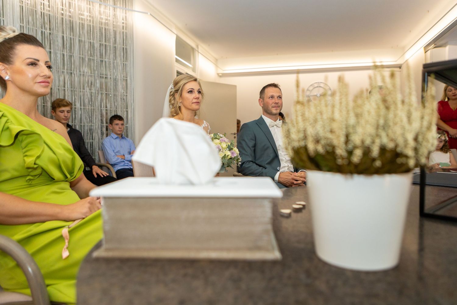 Dejan und Betty sitzen während der Trauung gemeinsam vor dem Trautisch.