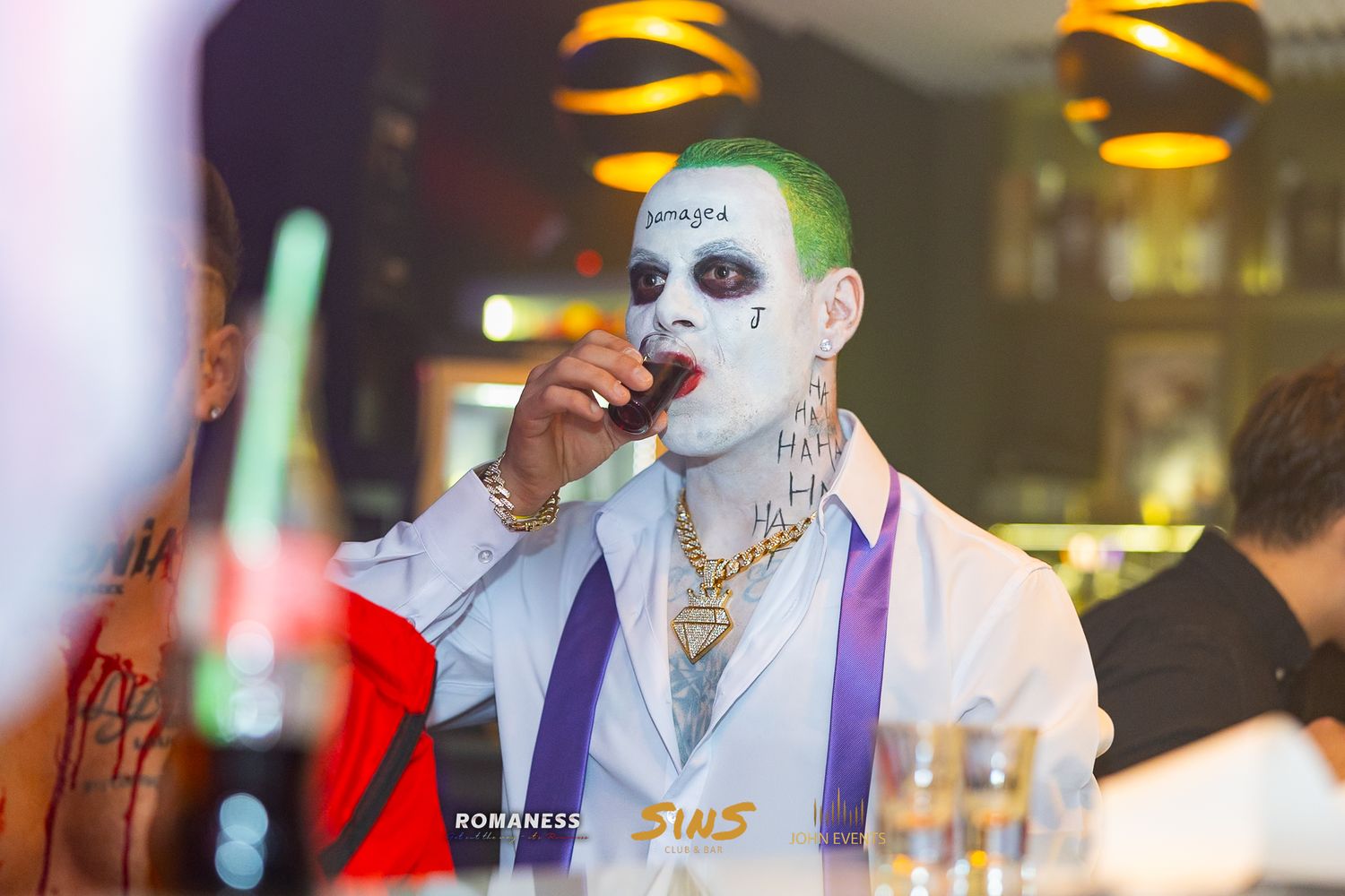 Ein als Joker geschminkter Gast im weißen Anzug an der Bar des Club Sins.