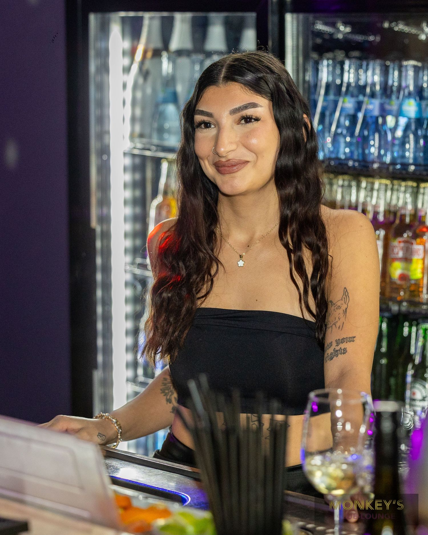 Eine dunkelhaarige Frau steht hinter der Bar im Monkey’s Club.