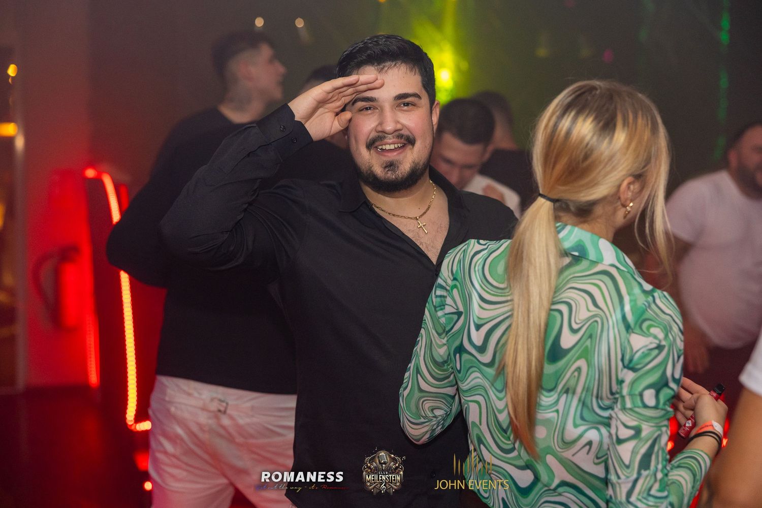 Ein Mann grüßt zwischen tanzenden Gästen im Club Meilenstein in die Kamera.