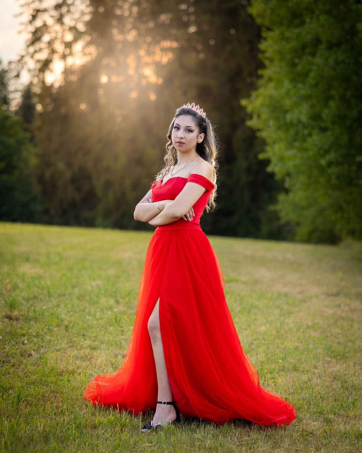 Lorena steht in einem roten Kleid ruhig auf der offenen Wiese