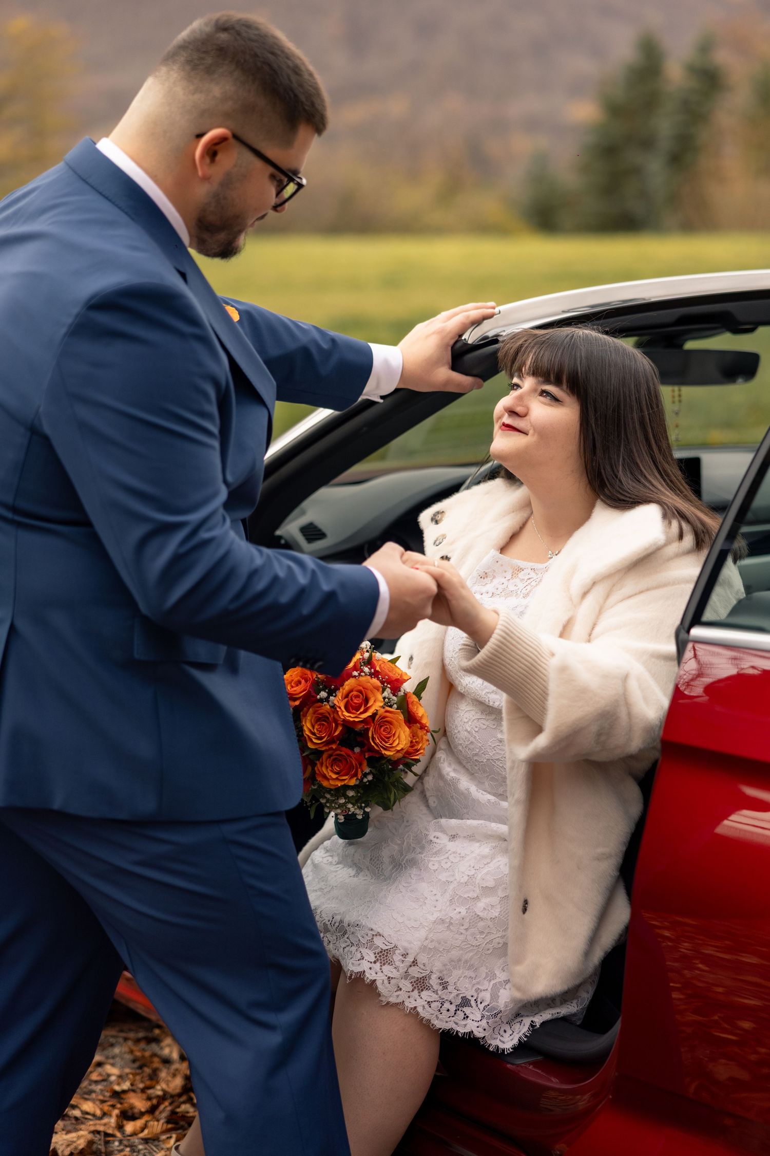 Braut und Bräutigam halten sich beim Aussteigen aus dem Auto an den Händen