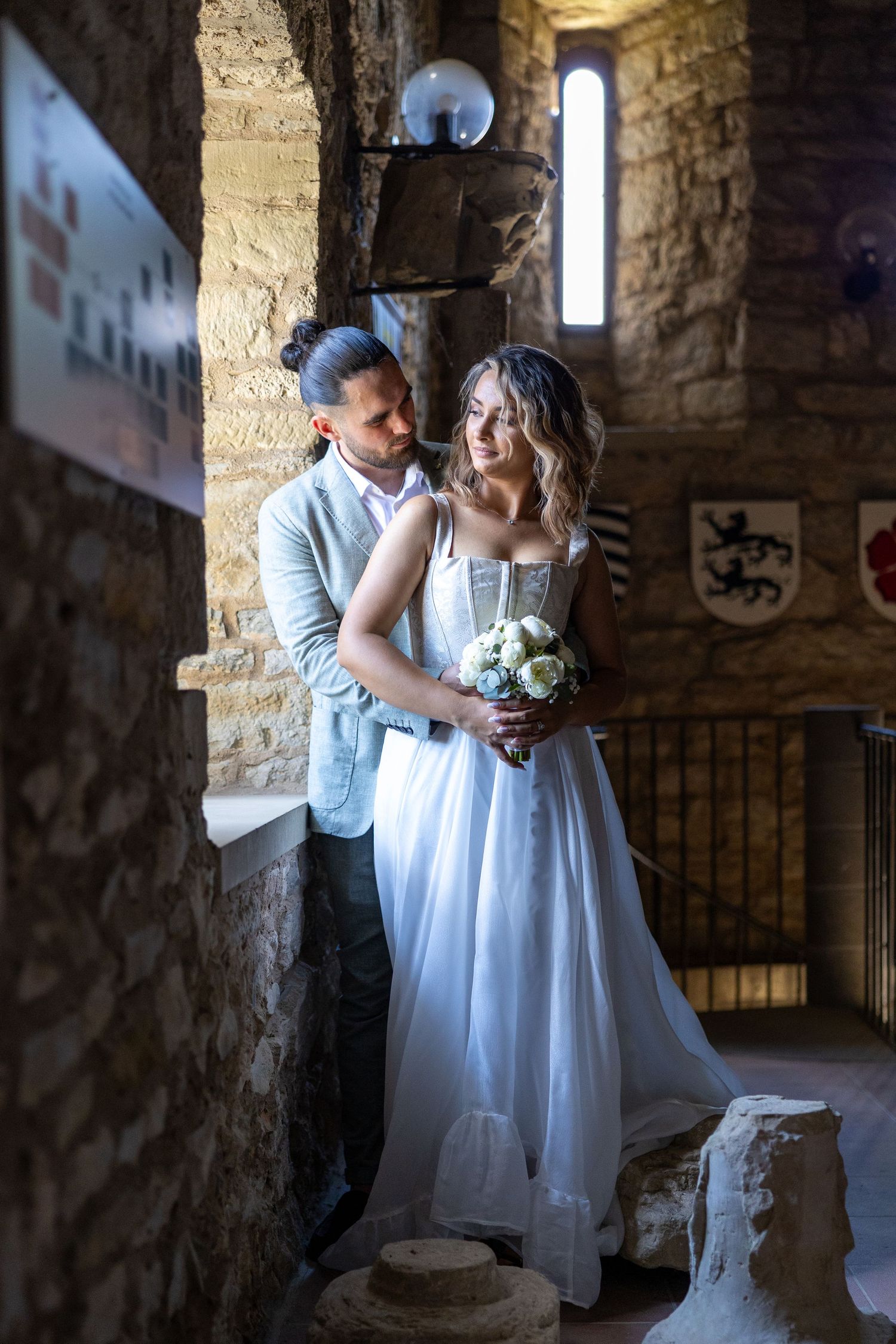 Naomi und Sergiu stehen eng umschlungen zwischen den Steinwänden des historischen Gebäudes.