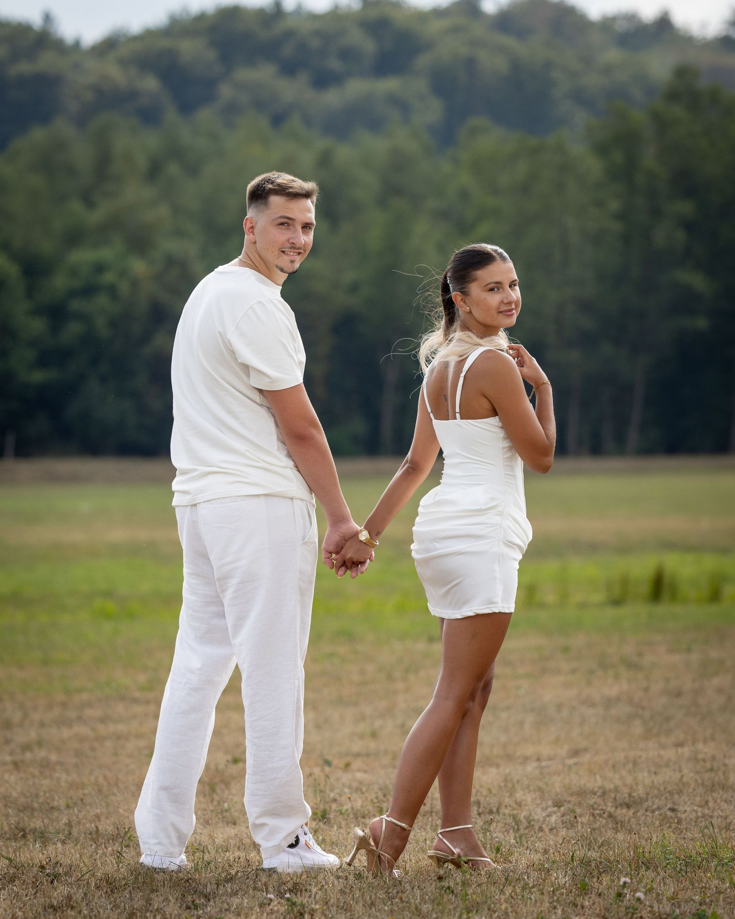 Bogdan und Lorena halten sich an den Händen und schauen beim Gehen über die Schulter zur Kamera.