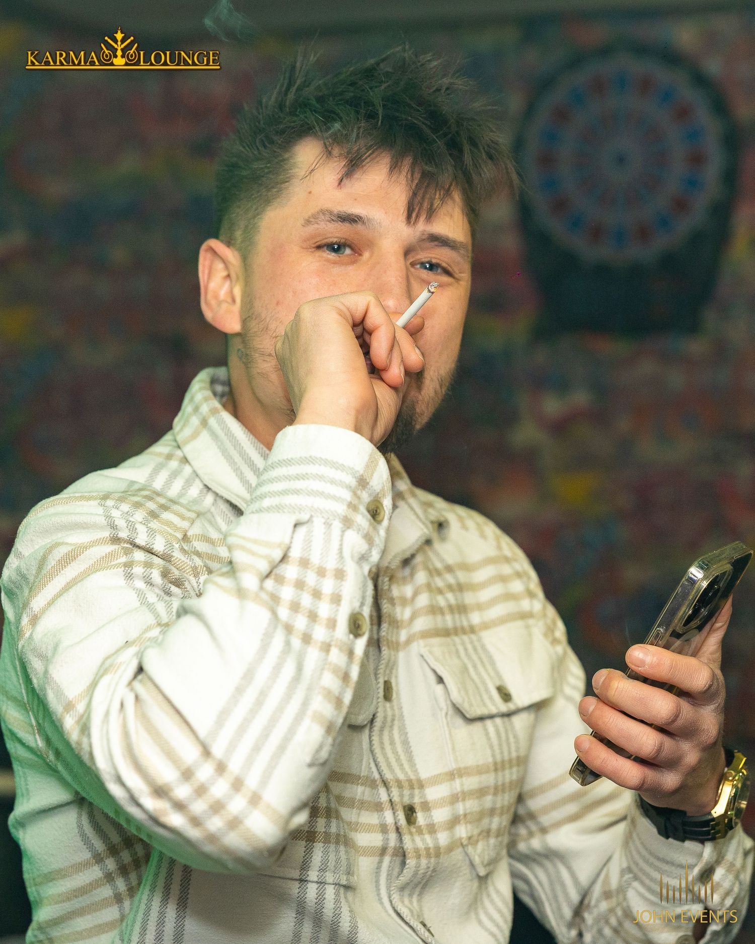 Ein Mann hält in der Karma Lounge ein Mikrofon vor den Mund und ein Telefon in der Hand.