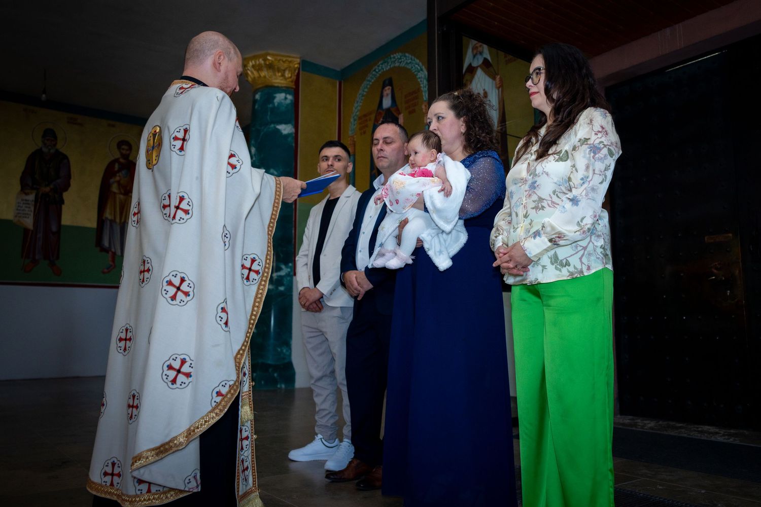 Der Priester begrüßt Emilia und ihre Familie vor der Taufe