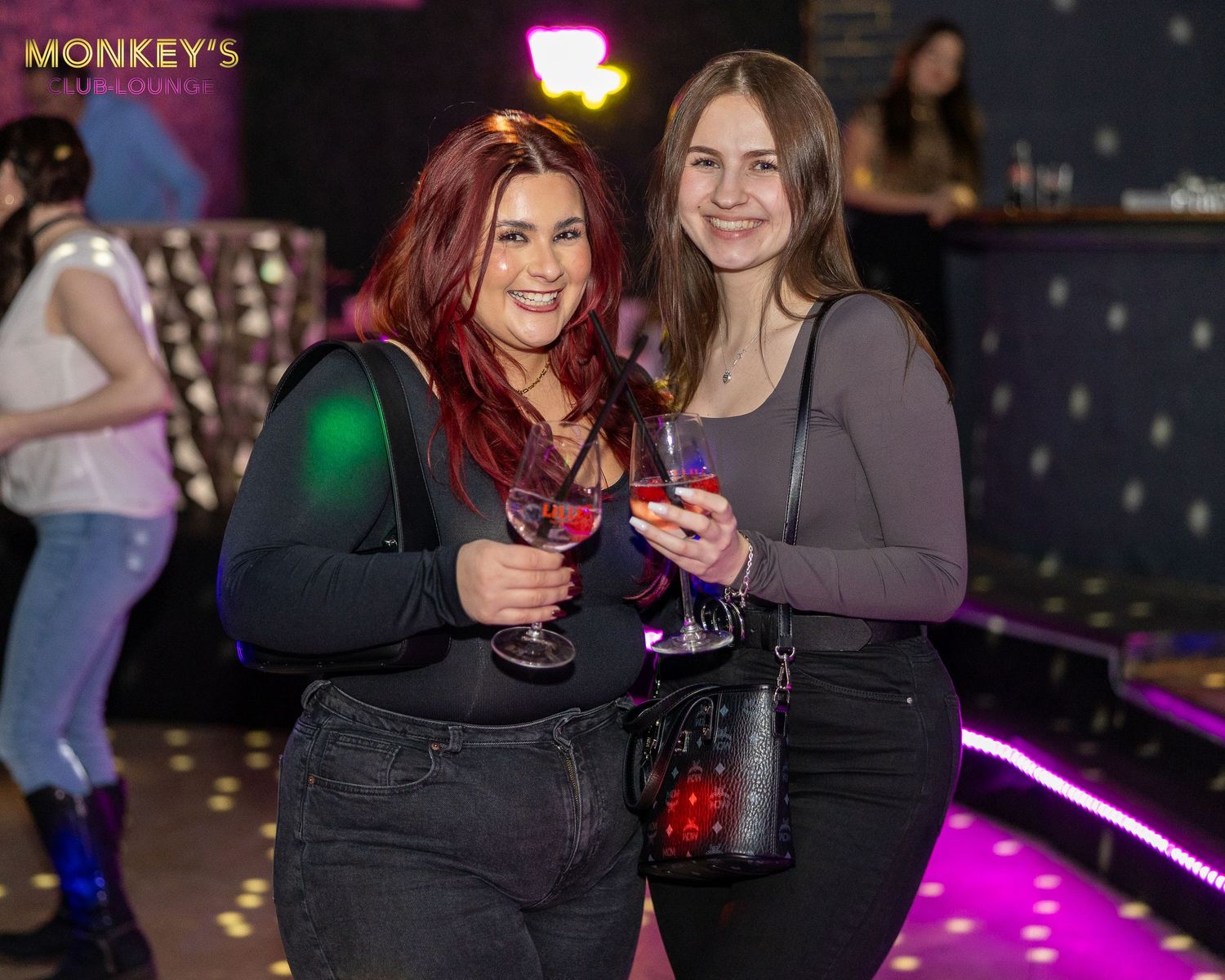 Zwei Frauen stehen mit ihren Getränken im Monkey’s Club zusammen.