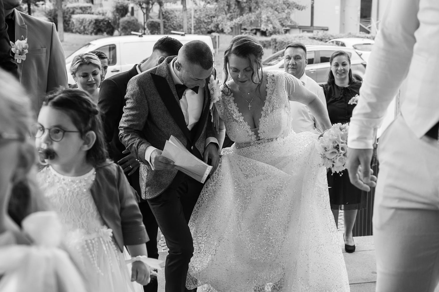 Black and white photo of a bride and groom walking together at their wedding ceremony outdoors.