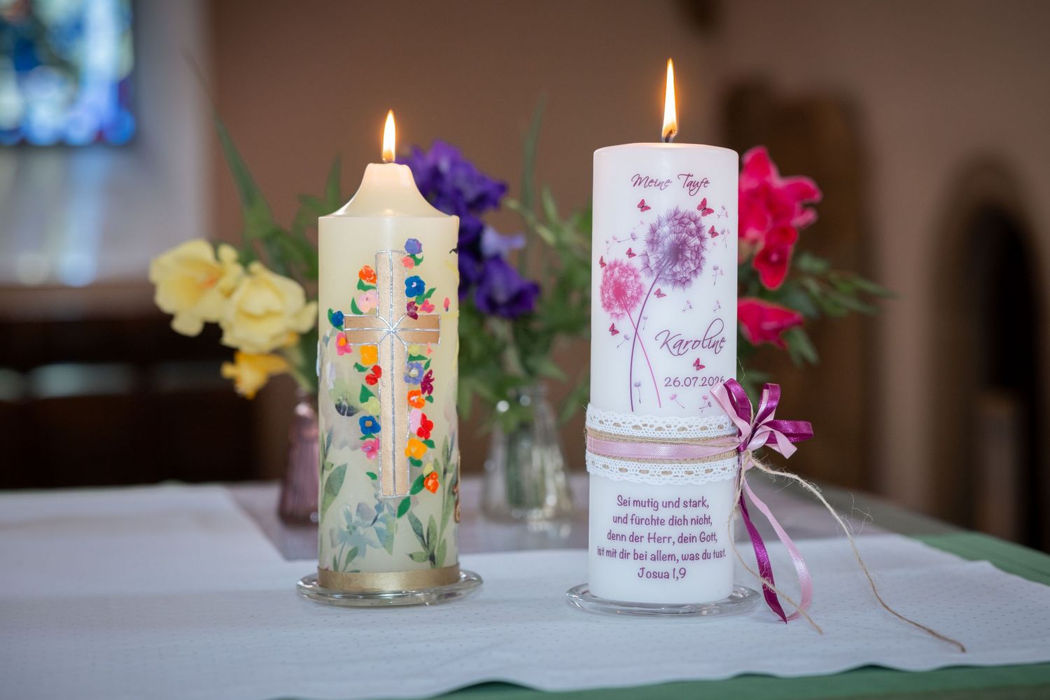 Zwei geschmückte Taufkerzen brennen in der Kirche.