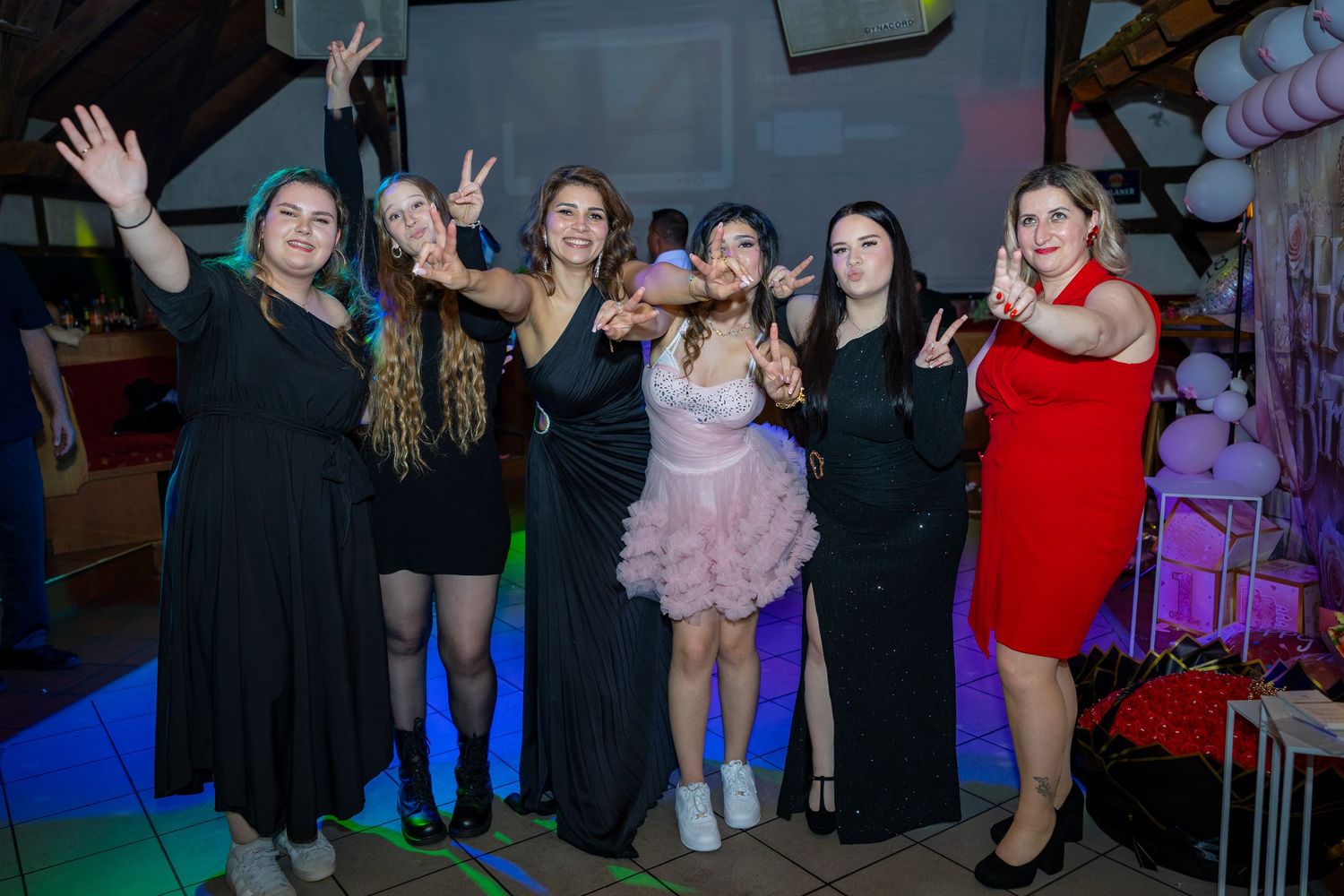 Eine Gruppe junger Frauen feiert gemeinsam vor der Geburtstagsdekoration.