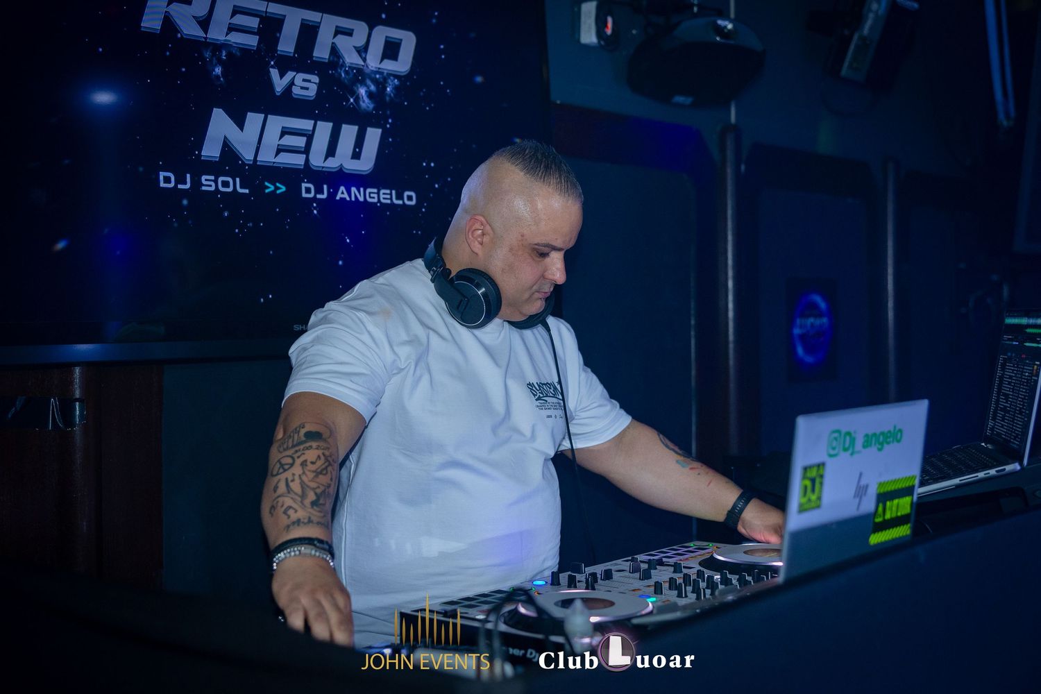 Ein DJ mit Kopfhörern bedient das Mischpult im blauen Licht des Club Luoar.