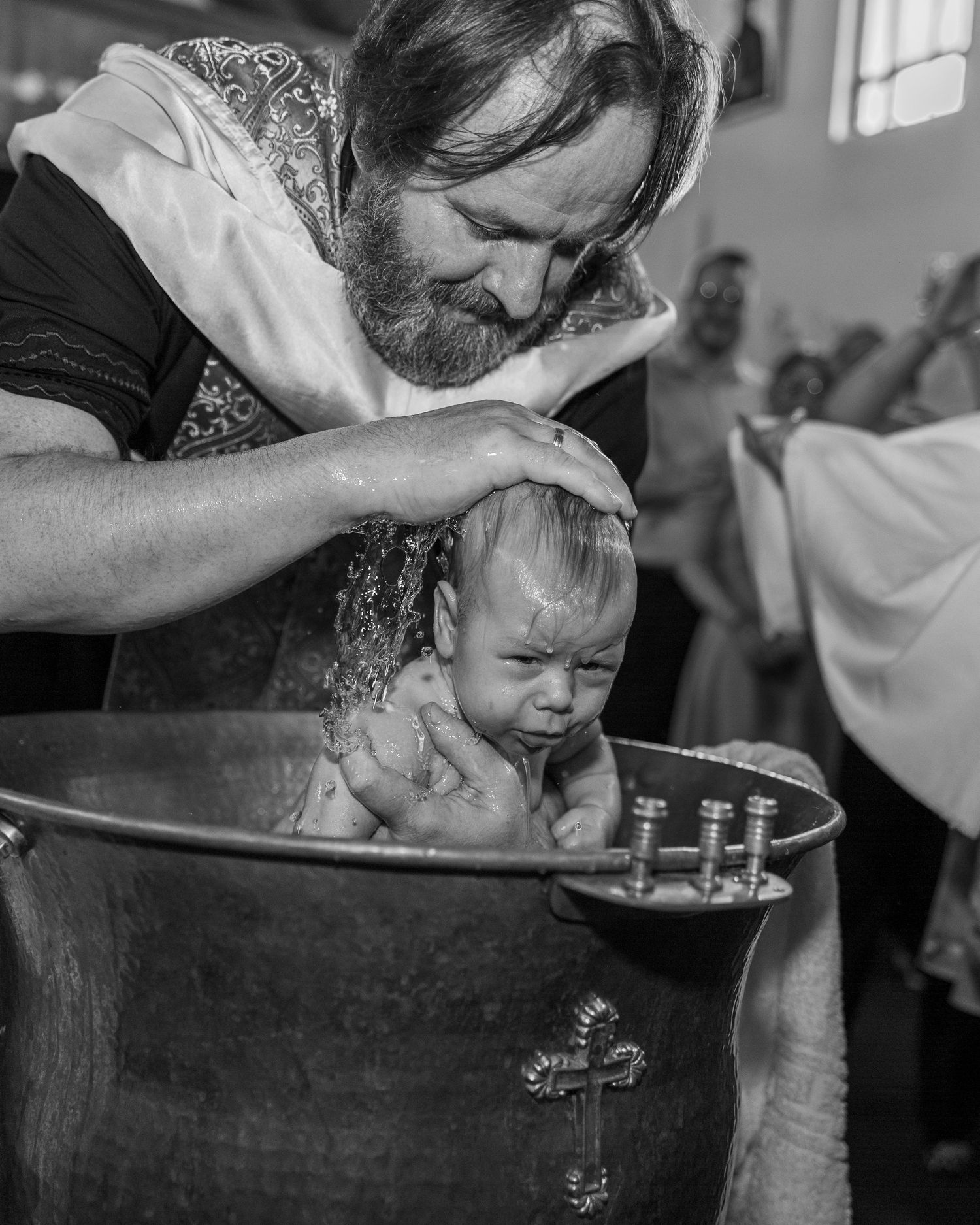 Schwarz-weiße Tauffotografie eines Babys während einer emotionalen Zeremonie in der Kirche.