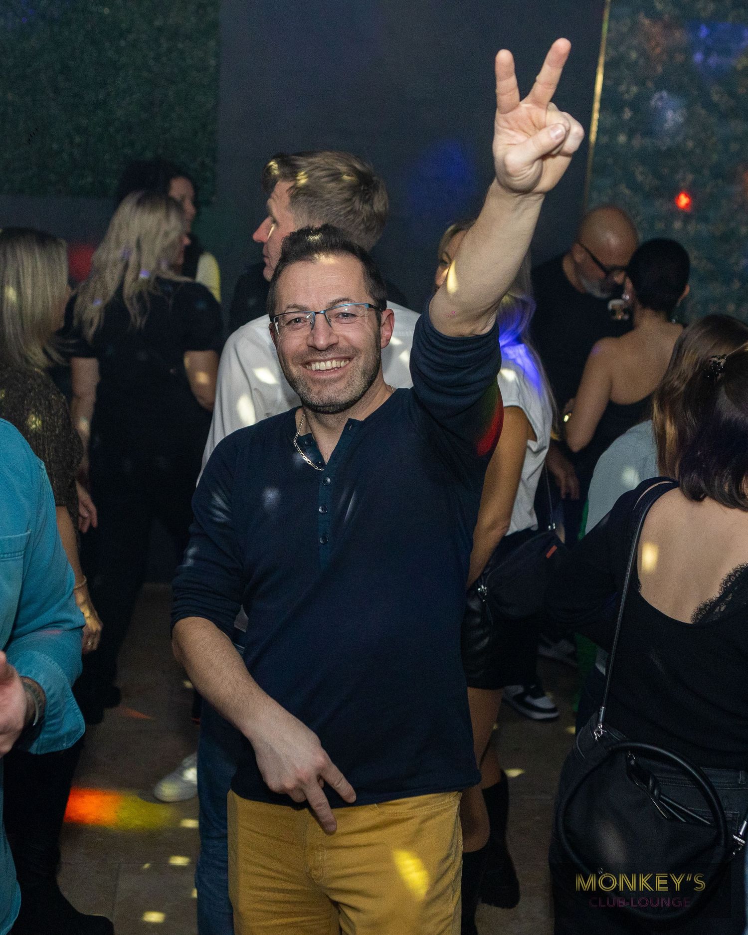 Ein Mann zeigt zwischen den Gästen im Monkey’s Club das Victory-Zeichen.