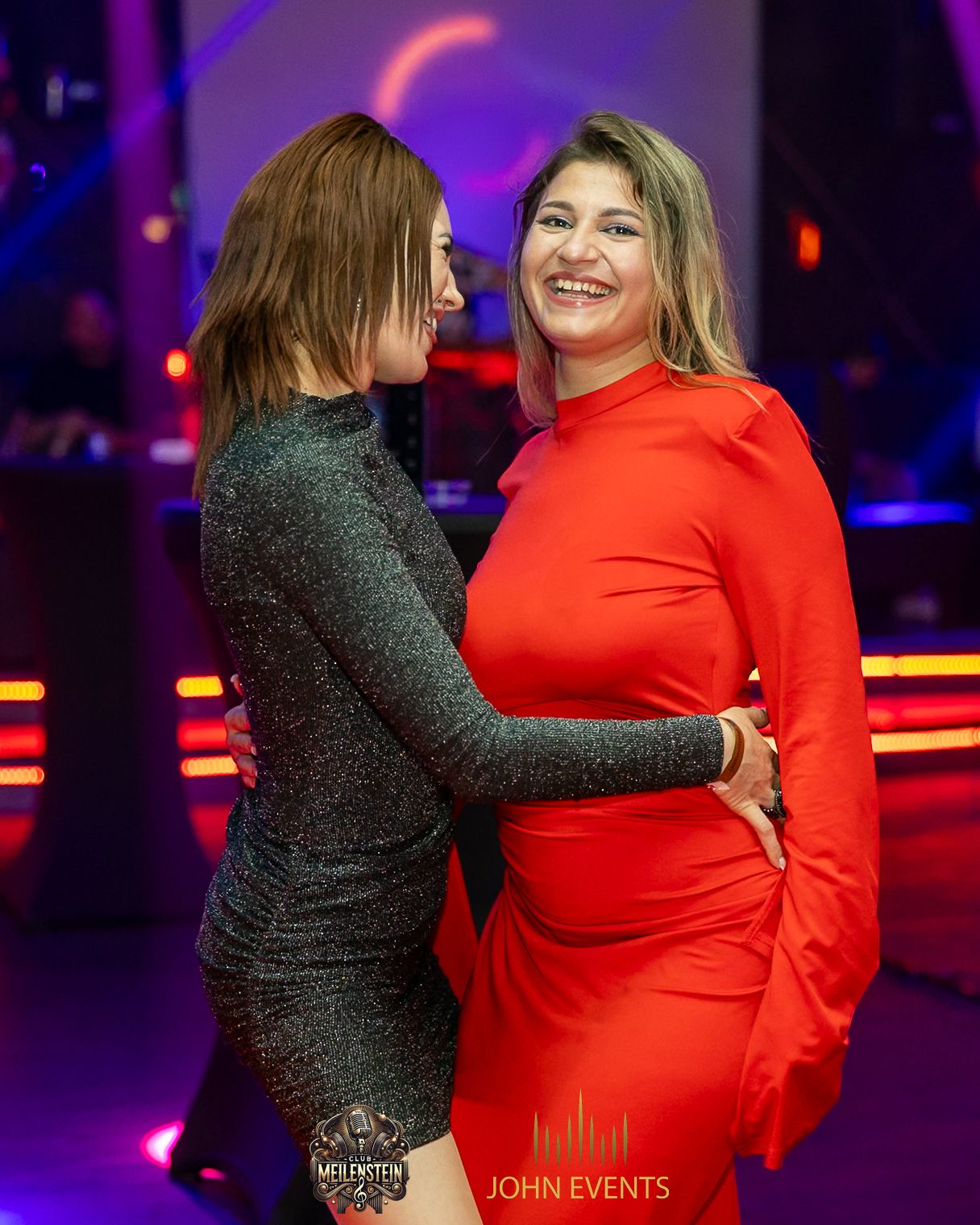 Zwei Frauen tanzen im Club Meilenstein, eine von ihnen trägt ein rotes Kleid.