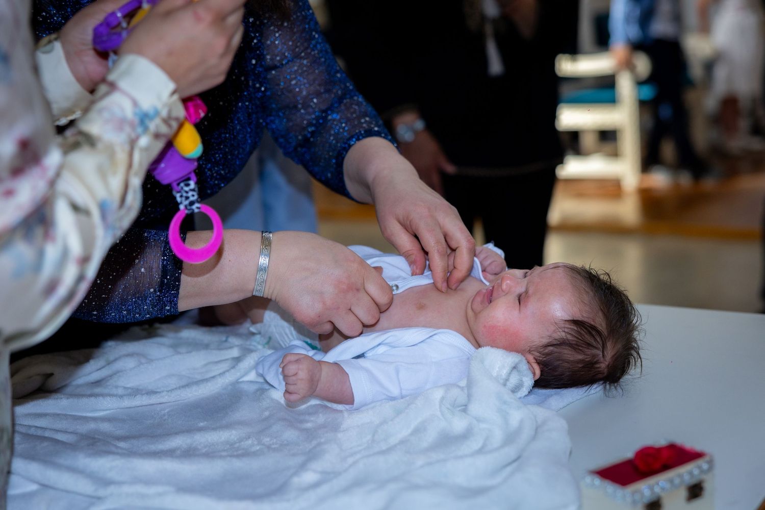 Hände bereiten Emilia behutsam auf den nächsten Schritt der Taufe vor