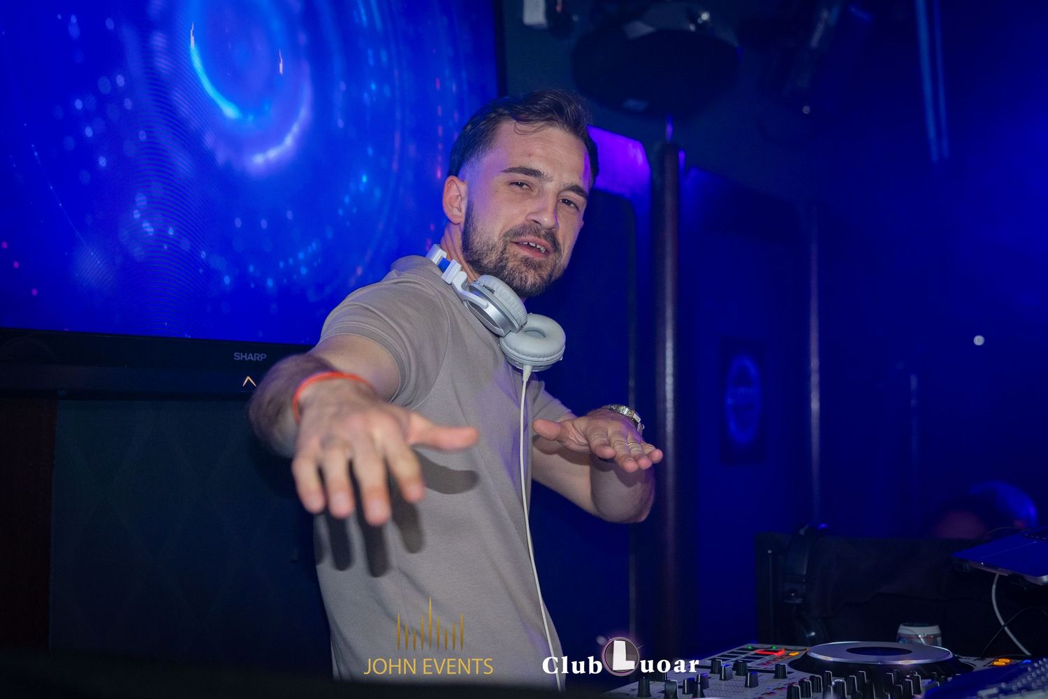Ein Mann mit Kopfhörern streckt im Club Luoar eine Hand zur Kamera aus.