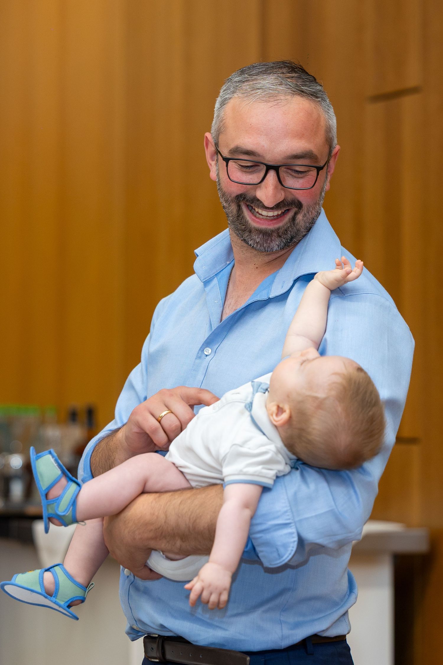 Ein Gast mit Brille hält ein lachendes Baby auf dem Arm.