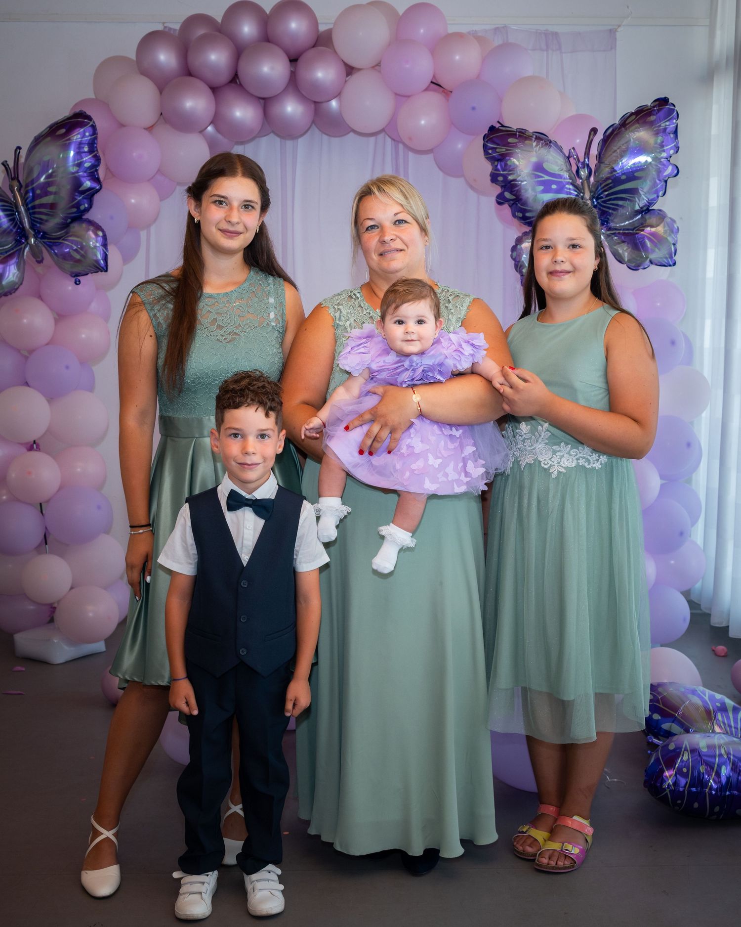Drei Frauen, ein Junge und Karoline im weißen Taufkleid vor der Ballondekoration.