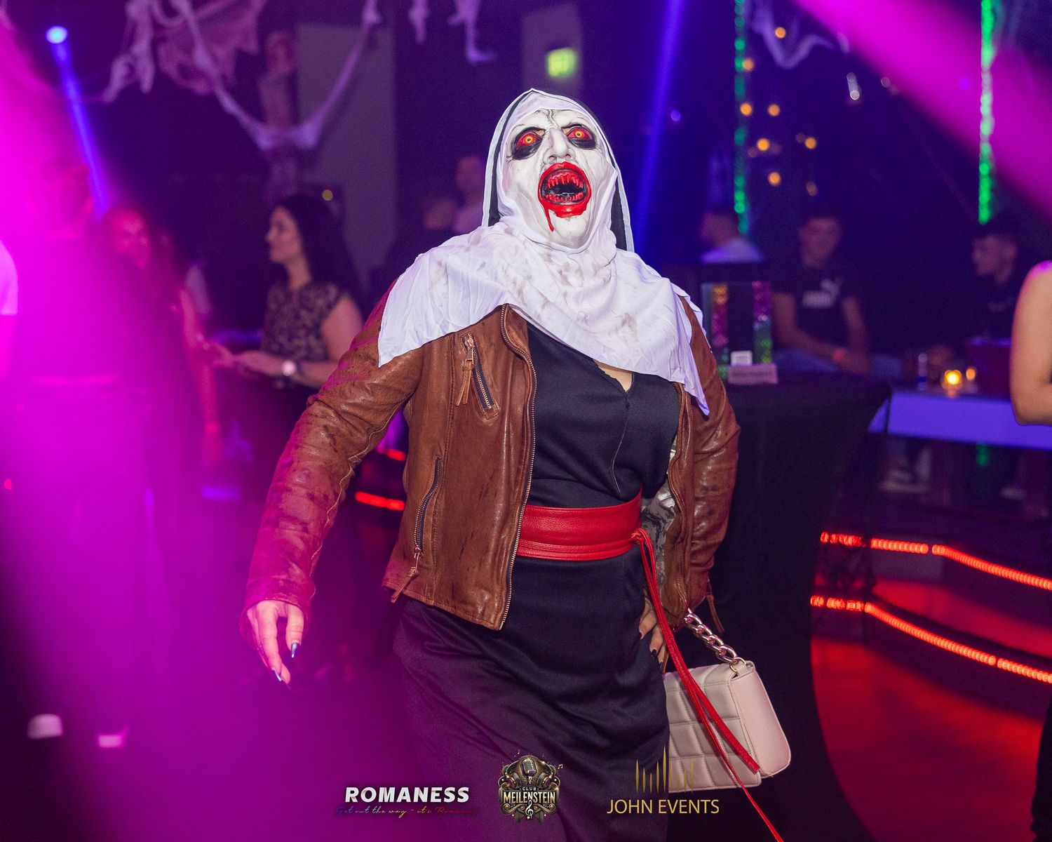 Ein Gast mit weißer Halloweenmaske tanzt im violetten Licht des Club Meilenstein.