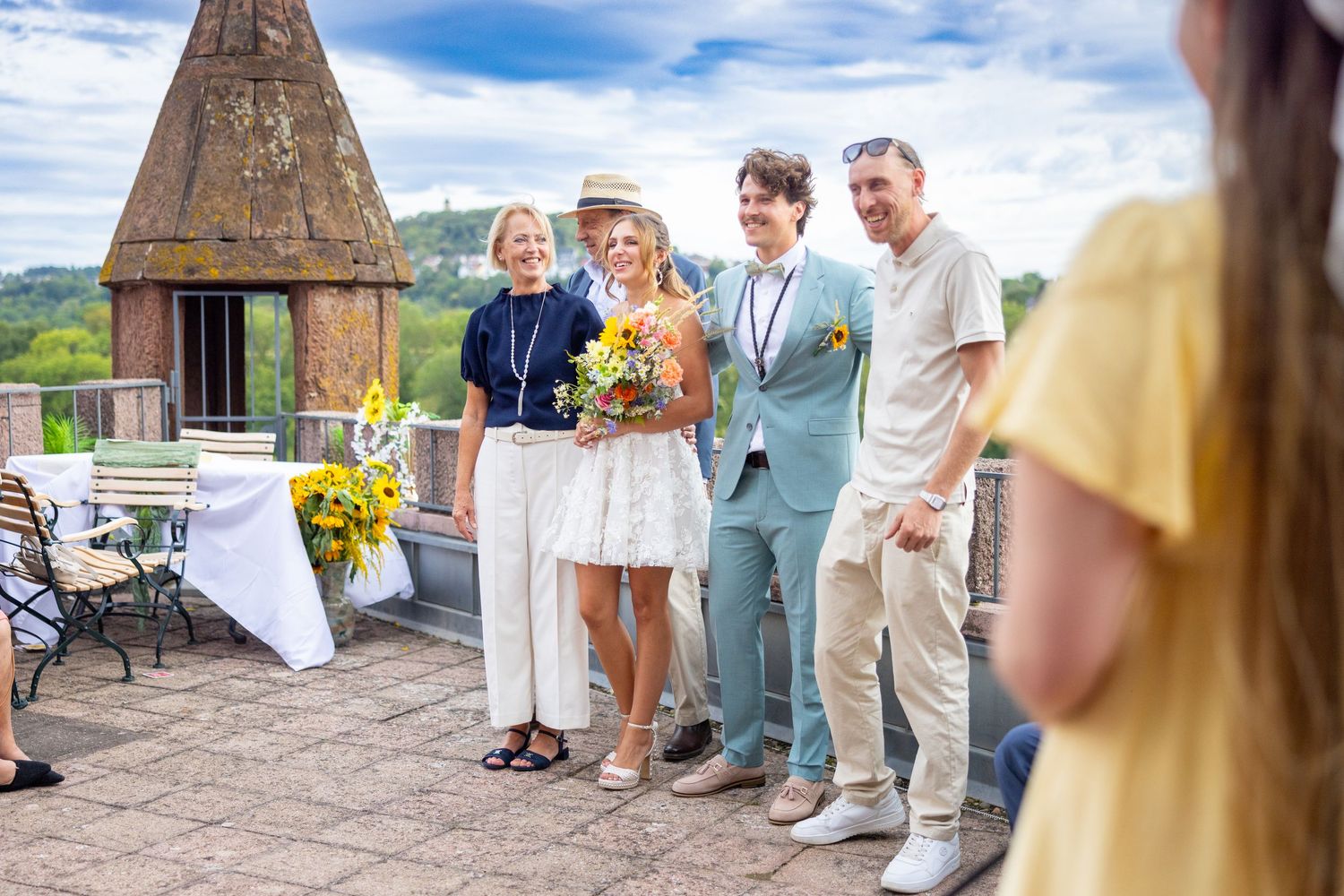 Das Brautpaar posiert mit den Gästen vor dem Turm des Schlosses.