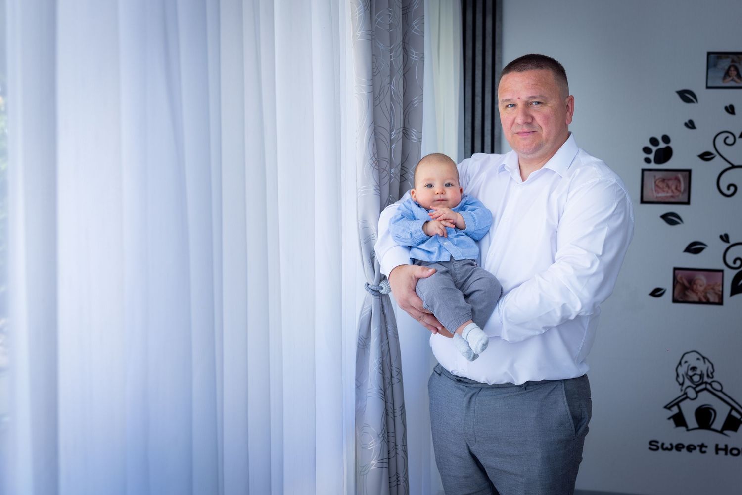 Milans Vater hält ihn im hellen Zimmer ruhig im Arm.
