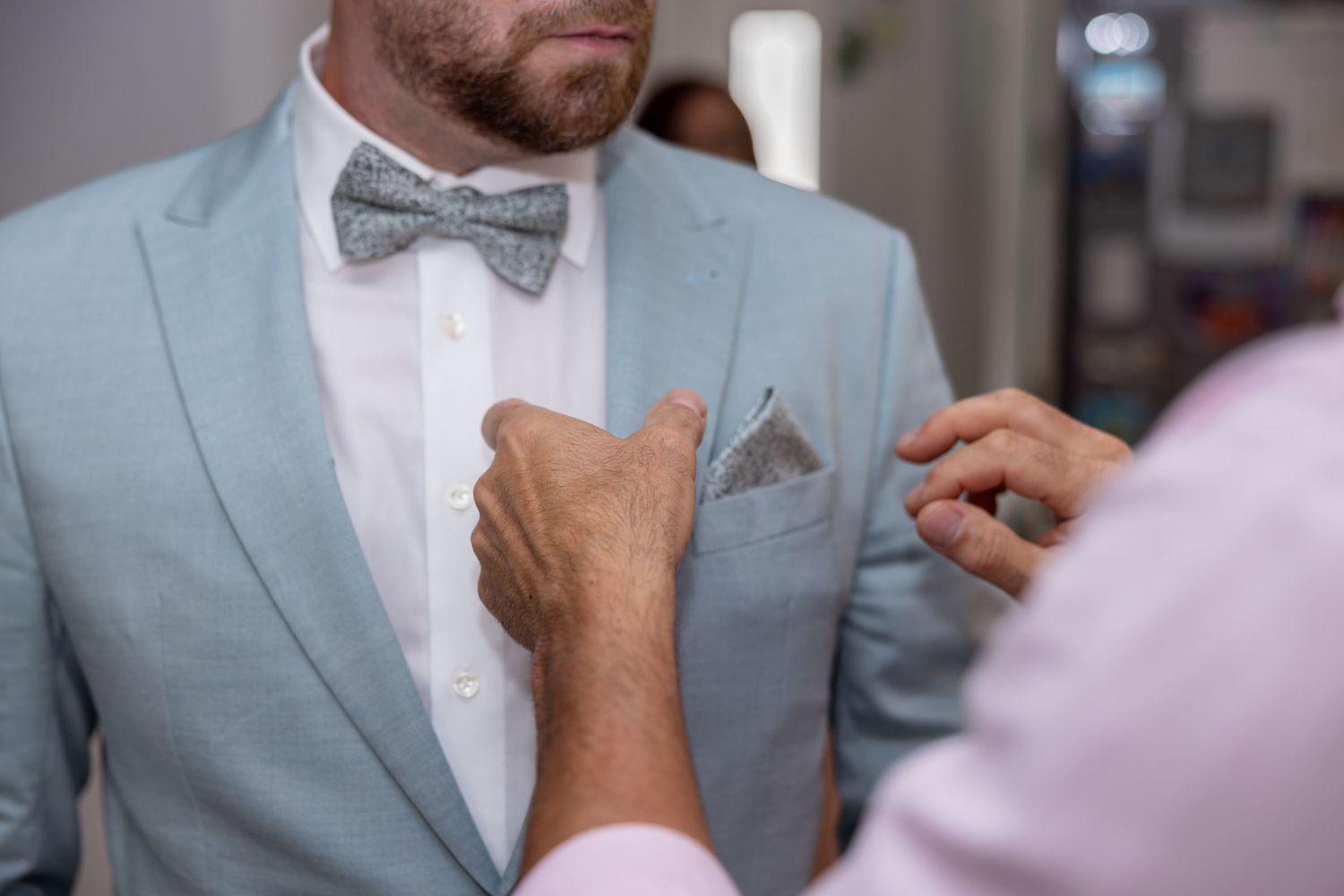 Nahaufnahme einer Boutonnière, die vor der Trauung am Anzug befestigt wird