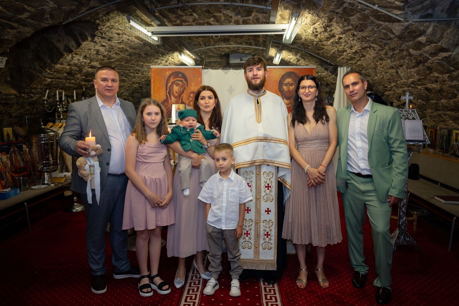 Familie und Kinder stehen mit dem Priester zum Gruppenfoto in der Kirche