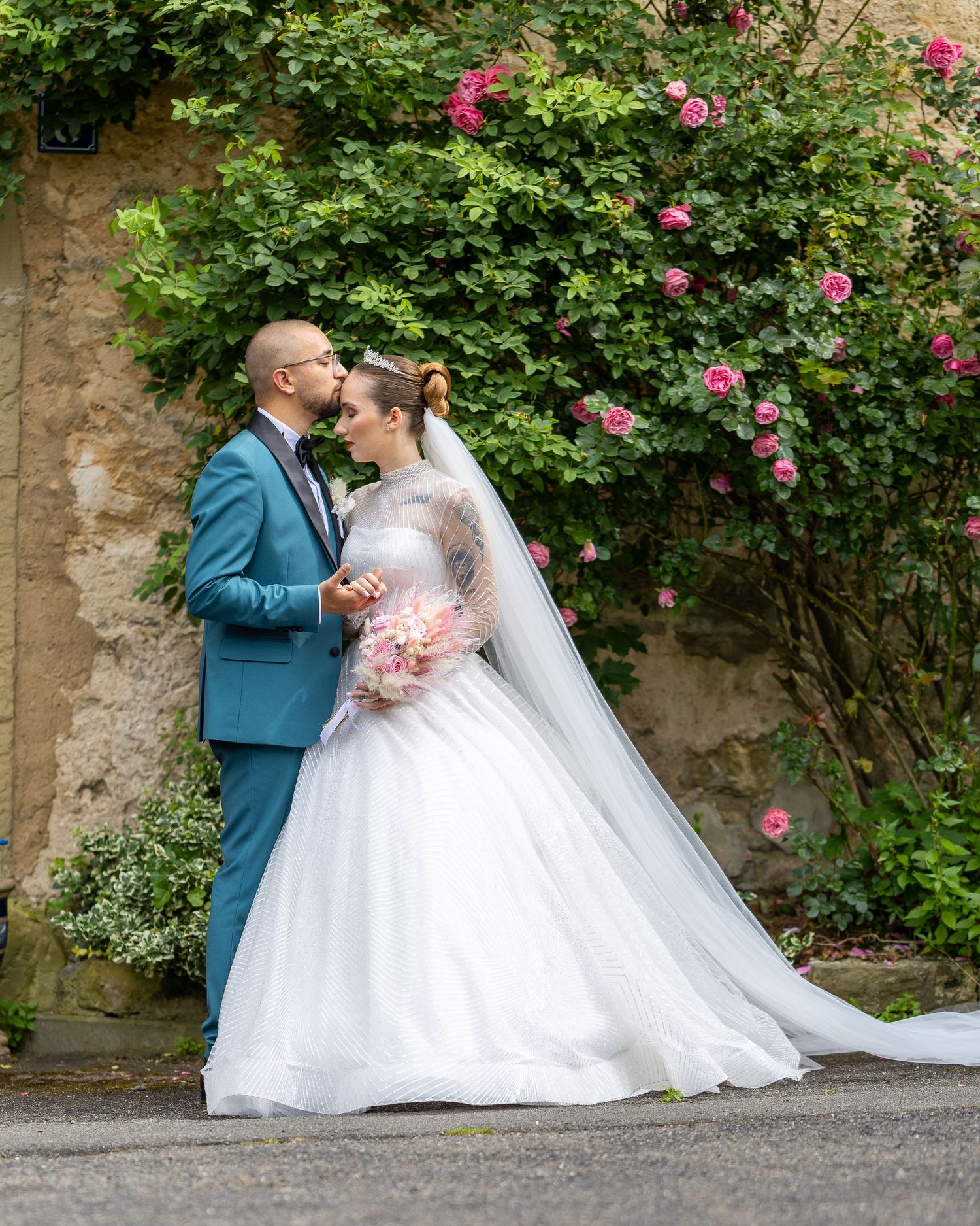 Radu und Saskia küssen sich vor einer blühenden Rosenwand.